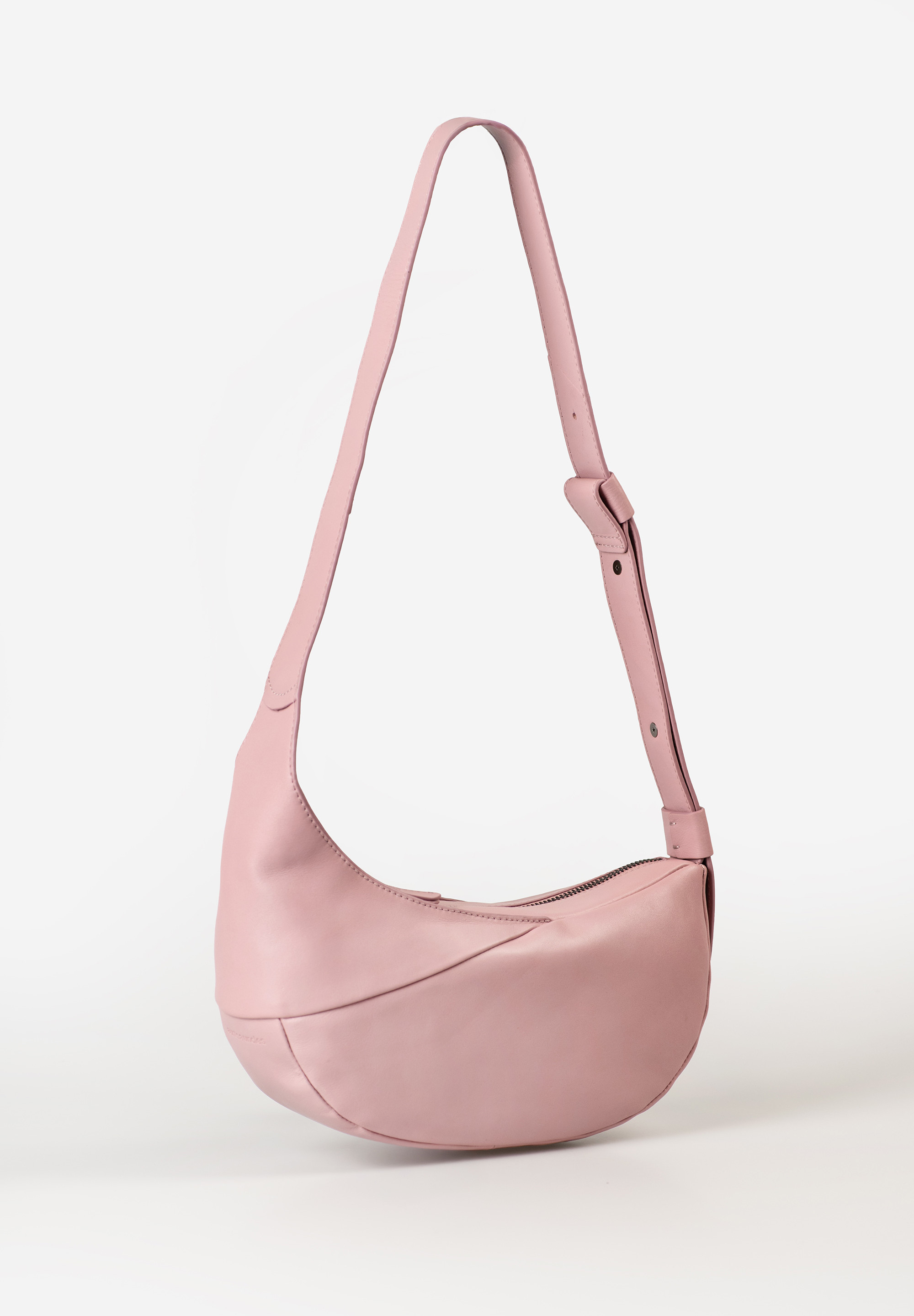 aunts & uncles – ORCHID Halfmoon Bag (cosmetic pink)
De Orchid uit de Jamie’s Orchard collectie van aunts & uncles is de kleinste Halfmoon Bag van de serie – compact, elegant en verrassend praktisch. Met haar minimalistische design en zachte premiumleer is ze een subtiele blikvanger die je overal mee naartoe neemt: van een etentje tot een avondje uit of een dag in de stad.

Waarom Orchid onmisbaar is
✔ Minimalistisch & functioneel: Orchid is klein van formaat (3,5 liter inhoud), maar biedt voldoende ruimte voor je dagelijkse essentials zoals telefoon, sleutels en portemonnee.
✔ Slim georganiseerd: Binnenin vind je een ritsvak, een ruim steekvak en een handig sleutelkoord. Alles blijft overzichtelijk én veilig opgeborgen.
✔ Veelzijdig draagcomfort: Dankzij de brede, in lengte verstelbare band kun je de tas dragen als schoudertas, crossbody of nonchalant op je rug.
✔ Elegant design: De halve maanvorm en de zachte cosmetic pink-kleur maken van Orchid een vrouwelijke, stijlvolle keuze voor elke gelegenheid.
✔ Hoogwaardige afwerking: Gemaakt van soepel, plantaardig gelooid en met de hand gewaxt rundsleer. Geleverd met stofzak voor veilige opberging.

Productspecificaties
Kleur: cosmetic pink (licht roze)

Inhoud: ca. 3,5 liter

Afmetingen: ca. 28 x 9 x 15 cm

Schouderbandlengte: ca. 70 – 95 cm (verstelbaar)

Materiaal: met de hand gewaxt, plantaardig gelooid rundleer

Voering: licht, bedrukt katoen

Indeling: hoofdvak met rits, binnenvak met rits, steekvak, sleutelkoord

Collectie: Jamie’s Orchard

Inclusief: beschermende stofzak

Onderhoud
Voor langdurige zachtheid en bescherming behandel je het leer regelmatig met een geschikt lederonderhoudsproduct. Zo blijft Orchid lang mooi en soepel.