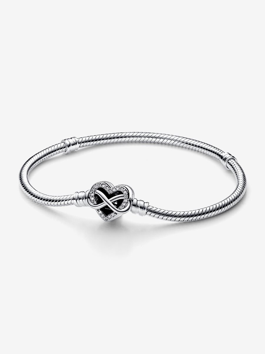 De Pandora Moments Sprankelende Snake Chain Armband (19 cm) met Hartsluiting vertegenwoordigt de eeuwige liefde die familie met elkaar verbindt en is een betekenisvol geschenk voor degenen die voor jou het belangrijkst zijn. De opengewerkte hartsluiting is bezet met stenen langs de rand van het motief en een asymmetrisch oneindigheidssymbool dat om het hart draait. De achterkant van de sluiting is gegraveerd met de boodschap, 'Family forever and Always'. De armband heeft twee schroefdraden (verhoogde bedelverdelers) die hem in drie delen verdelen.