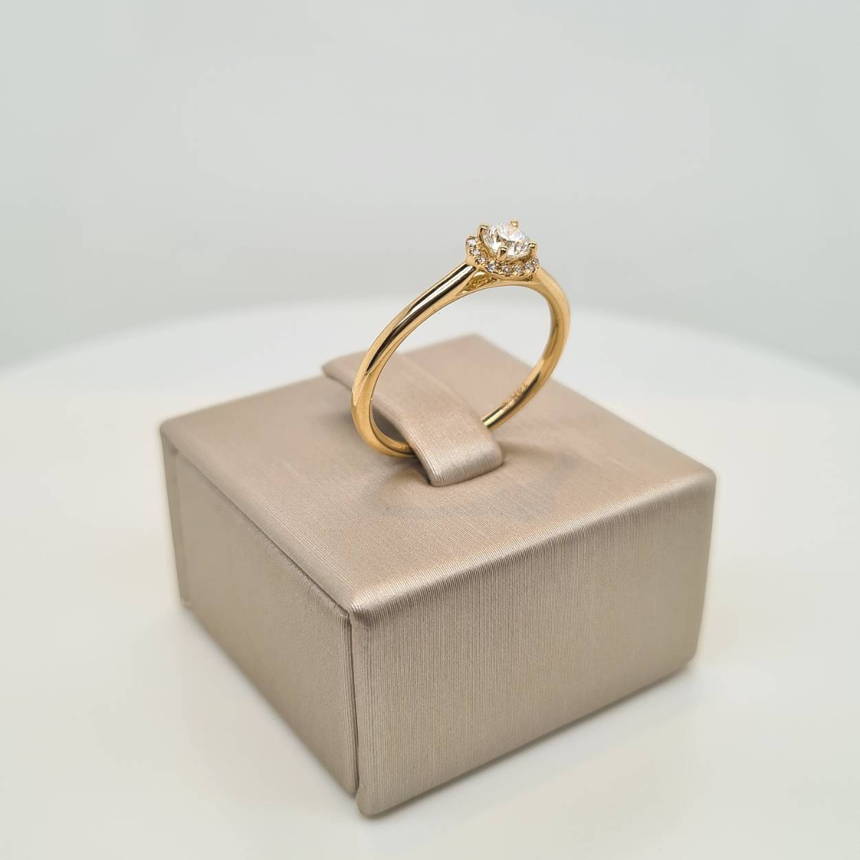 14krt geelgouden ring met briljant geslepen diamant in vierkante entourage zetting. Dankzij de verhoogde zetting, is de ring goed te combineren met een gouden of diamanten aanschuifring.
 
Middensteen 0.18 crt