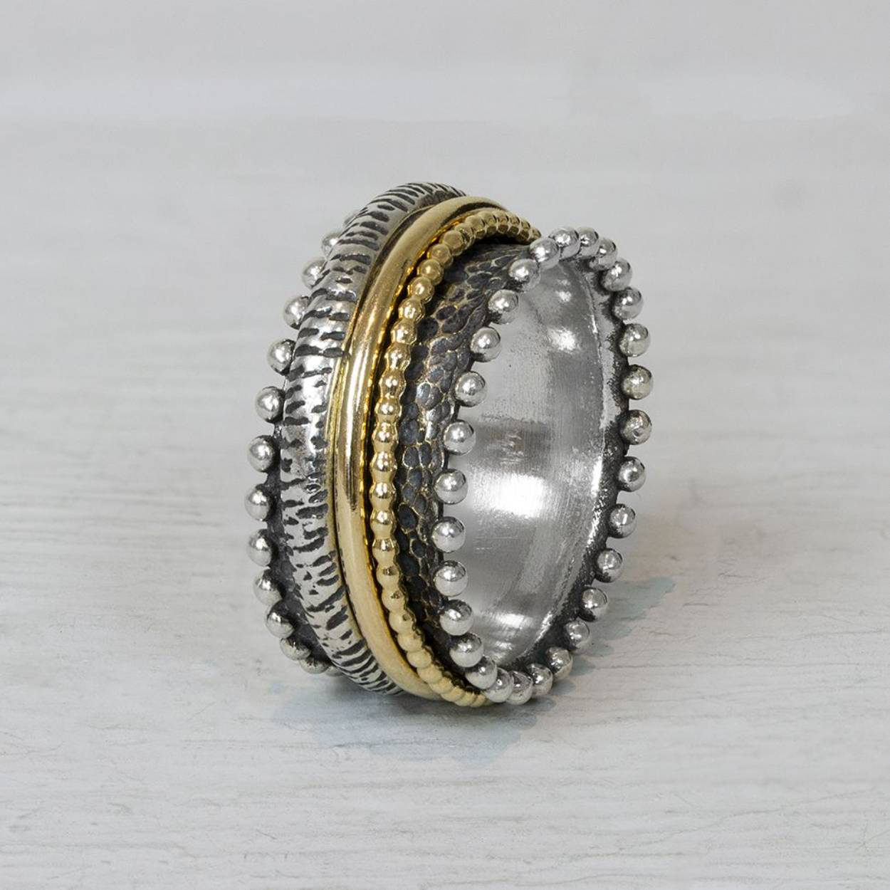 Ring gemaakt van geoxideerd zilver en Goldfilled. Deze ring heeft goldfilled bandjes die in het midden kunnen draaien. De bolletjes aan de zijkant maken deze ring extra speels.