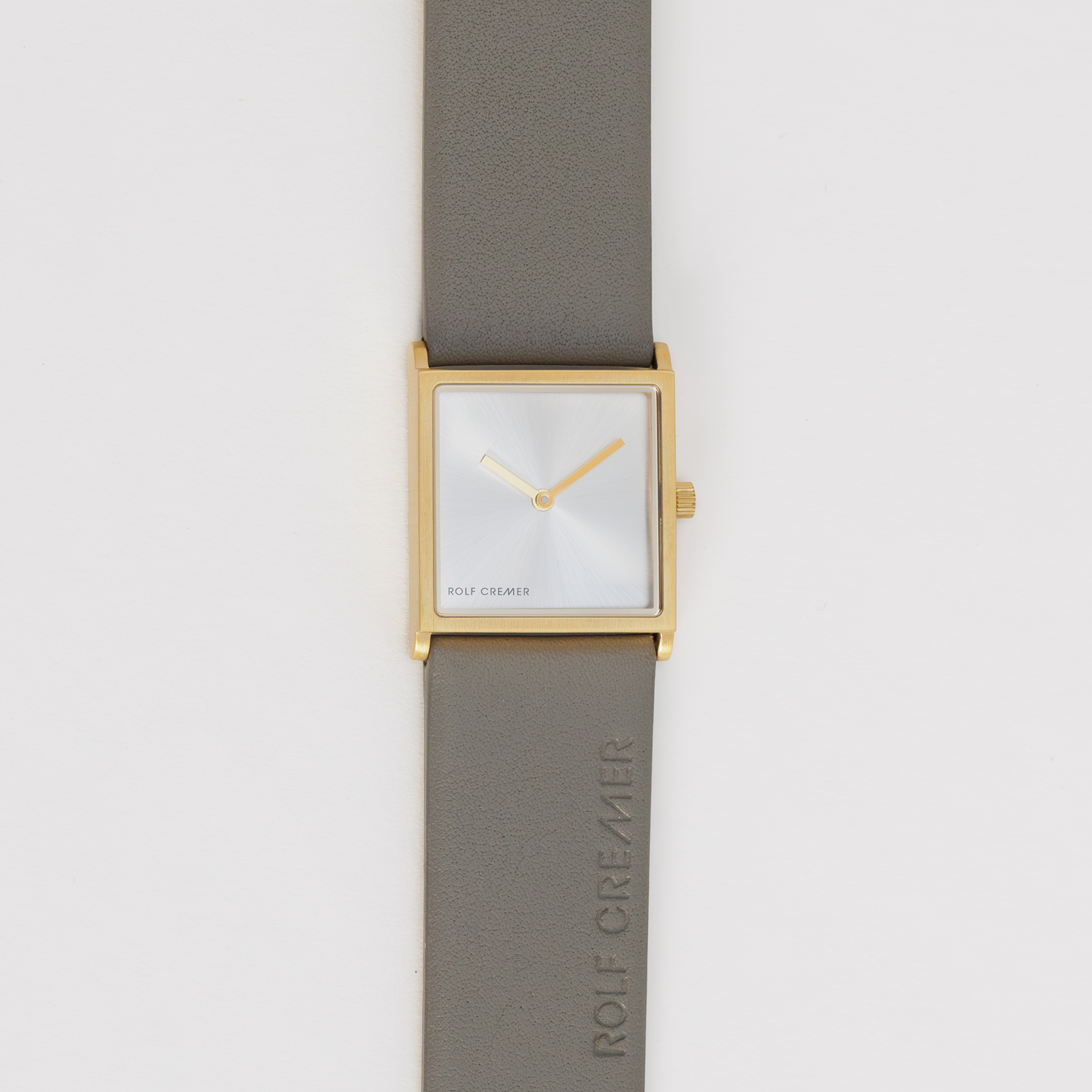 Vierkant horloge met goudkleurige kast en lichte wijzerplaat, lichtbruine leren band.
