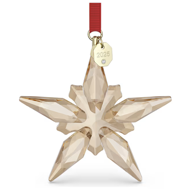 Omarm een van de traditionele hoogtepunten van het seizoen met dit Swarovski Annual Edition Ornament. Het stervormige design, dat aan een rood ripsband lint met champagnegoudkleurige accenten hangt, is precisiegeslepen met 190 lichtvangende facetten en belichaamt op beeldschone wijze de complexe eenvoud en technische vaardigheid van Swarovski. Het goudkleurige ontwerp is afgewerkt met een gravure van het jaar 2025 op het label. Perfect om op te hangen aan een kerstboom, op een raam of ergens anders in huis. Dit ornament is een werkelijk wonderbaarlijke manier om uw feestdagen te vieren. Decoratieobject. Geen speelgoed. Niet geschikt voor kinderen jonger dan 15 jaar.