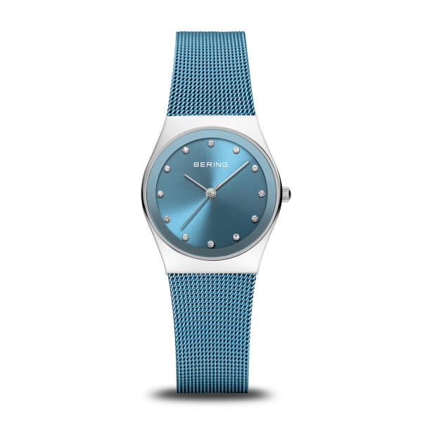  Dit horloge is een stijlvol statement van moderne helderheid. De ovale kast van gepolijst roestvrij staal omlijst op elegante wijze de arctischblauwe sunray-wijzerplaat, die prachtig schittert in het licht. Het subtiele kleurverloop vangt het licht op verfijnde wijze en doet denken aan de heldere hemel boven de ijzige uitgestrektheid van het noorden. Twaalf fonkelende kristallen markeren de uren &ndash; subtiel, maar opvallend.  Met een kastdikte van slechts 5 mm ligt het horloge plat en comfortabel om de pols, en benadrukt het de vrouwelijke lichtheid van het ontwerp. De fijn geweven Milanese band in intens blauw versterkt het moderne karakter van het horloge en zorgt met de vouwsluiting voor een veilige en aangename pasvorm.  Het platte, krasbestendige saffierglas beschermt de wijzerplaat betrouwbaar tegen krassen, terwijl een nauwkeurig quartz uurwerk aan de binnenkant zorgt voor een precieze tijdweergave. Met een waterbestendigheid van 3 ATM is dit model ook perfect geschikt voor dagelijks gebruik. 