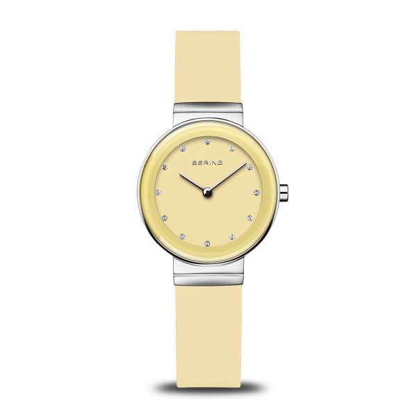  Dit dameshorloge uit de Classic collectie van BERING brengt een frisse kleuraccent in het dagelijks leven. De gele wijzerplaat met sunray-afwerking straalt bij elke lichtinval een levendige glans uit, elegant benadrukt door twaalf fonkelende kristalindexen. Slanke wijzers onderstrepen het minimalistische karakter en geven het horloge een moderne en tijdloze uitstraling.  De 29 mm kast van gepolijst zilverkleurig roestvrij staal vormt een perfecte combinatie met de zachte, lichtgele siliconen band, die comfortabel om de pols zit en veilig wordt gesloten met een klassieke gespsluiting.  Het platte saffierglas beschermt de wijzerplaat betrouwbaar tegen krassen, terwijl het nauwkeurige quartz uurwerk binnenin zorgt voor een exacte tijdweergave. Met een waterbestendigheid van 3 ATM is dit model een vrolijke metgezel die zomerse lichtheid verenigt met de heldere Scandinavische designtaal. 