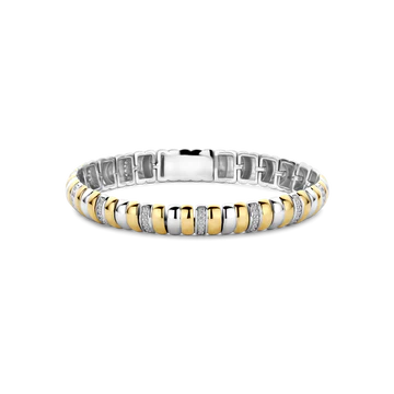 Geniet van sculpturale glans met deze TI SENTO goudkleurig vergulde zilveren armband 23081ZY. Vervaardigd uit 925 sterling zilver, wisselen de gedurfde schakels spiegelend platinakleurig verguld af met stralend goudkleurig verguld, wat een harmonieus ritme rondom de pols creëert. Een centraal pavé-gezette accentsteen voegt verfijnde sprankeling toe en versterkt het contrast tussen warmte en glans. Ontworpen om op zichzelf te schitteren of te combineren in een zorgvuldig samengestelde stack, gaat hij moeiteloos van gestructureerde daglooks naar verfijnde avondoutfits. Nikkelvrij en hypoallergeen, voor luxe comfort in elk detail.