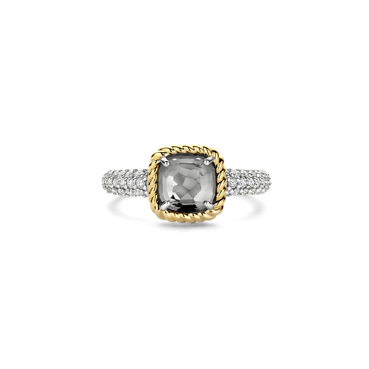 Omarm tonale elegantie met deze TI SENTO vergulde ring 12399GG. Vervaardigd uit 925 sterling zilver toont dit kussenvormige ontwerp een transparante grijze steen, fijn gefacetteerd en omlijst door een gedraaide goudkleurige klauwzetting. De platinakleurig vergulde band is pavé gezet met briljant geslepen witte zirconia en voegt een zachte fonkeling toe die de mysterieuze diepte van de steen versterkt. Elegant in zijn eenvoud verenigt deze ring vintage charme met moderne veelzijdigheid, perfect om alleen te dragen of als onderdeel van een zorgvuldig samengestelde ringstack. Nikkelvrij en hypoallergeen, hij biedt blijvend comfort en moeiteloze verfijning.