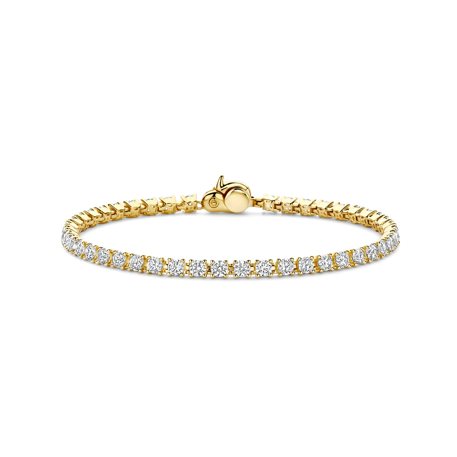 Omarm ingetogen luxe met deze TI SENTO vergulde armband 2995ZY. Vervaardigd uit hoogwaardig 925 sterling zilver en afgewerkt met een rijke goudkleurige vergulding is deze verfijnde tennisarmband voorzien van een enkele rij van 2,5 mm witte zirconia. Elke steen is met de hand gezet in delicate klauwzettingen en biedt een gracieuze fonkeling die het licht moeiteloos vangt. Het slanke silhouet geeft dit sieraad een tijdloze, vrouwelijke uitstraling. Ideaal voor dagelijks gebruik of elegante gelegenheden. De veilige sluiting is naadloos geïntegreerd voor een gepolijste, ononderbroken afwerking. Perfect om alleen te dragen als statement of gecombineerd met andere armbanden, verrijkt het iedere sieradencollectie met zijn klassieke design. Een subtiel icoon van sieradenkunst, ontworpen voor wie detail en vakmanschap waardeert. Nikkelvrij en hypoallergeen, het biedt blijvend comfort en stralende glans.