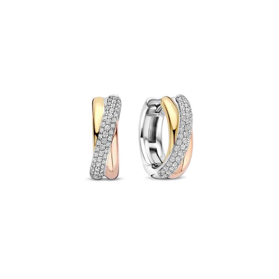 Vier moderne balans met deze TI SENTO tricolour oorbellen 78012ZT. Vervaardigd uit 925 sterling zilver combineert iedere 16 mm hoop stralend geelgoudkleurig, zacht rosegoudkleurig en koel platinakleurig verguld in een vloeiend crossover-ontwerp. Een sierlijk lint van pavé gezette witte zirconia loopt langs de voorkant en vangt het licht bij iedere beweging. Het sculpturale silhouet zorgt voor diepte en contrast, terwijl het compacte formaat ze ideaal maakt voor dagelijks gebruik met een verfijnde twist. Nikkelvrij en hypoallergeen, deze oorbellen bieden blijvend comfort en geraffineerde schittering voor elke gelegenheid.