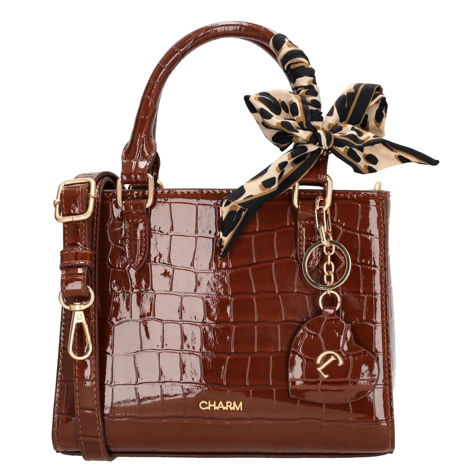 De Charm London Knightsbridge Handtas is een elegante en vrouwelijke tas met een glanzende laklook in croco-reliëf. Dankzij de twee stevige handvatten draag je deze tas comfortabel in de hand of over de arm. Het stijlvolle design maakt de tas perfect voor zowel dagelijks gebruik als speciale gelegenheden.

De tas sluit met een ritssluiting en heeft aan de binnenkant een ritsvak en een telefoonvak voor een overzichtelijke indeling. Je kunt de tas ook als schoudertas dragen dankzij de verstelbare en afneembare schouderband. De goudkleurige details zorgen voor een luxe uitstraling. Als extra detail is de tas afgewerkt met een hartvormige hanger met spiegeltje en een decoratief sjaaltje dat je op verschillende manieren kunt dragen.

Kenmerken:

Laklook met croco-reliëf

Ritssluiting

Twee handvatten

Ritsvak en telefoonvak aan de binnenkant

Verstelbare en afneembare schouderband

Goudkleurige details

Inclusief hartvormige hanger met spiegel

Decoratief sjaaltje, op meerdere manieren te dragen