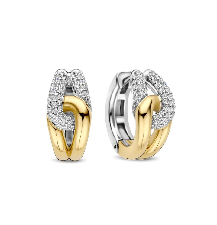 Stap in de spotlight met deze sculpturale TI SENTO vergulde oorbellen 78033ZY. Vervaardigd uit 925 sterling zilver, wikkelen ze zich om het oor in een gedurfde draai van contrast en schittering. De ene zijde is goudkleurig verguld, terwijl de andere zijde platinakleurig verguld is en bezet met twee gebogen rijen briljant geslepen witte zirconia. Het verstrengelde ontwerp vangt het licht vanuit elke hoek en zorgt voor een perfecte balans tussen textuur, fonkeling en verfijning. Nikkelvrij en hypoallergeen, deze oorbellen zijn gemaakt voor luxe die de hele dag door gedragen kan worden, met een zelfverzekerde uitstraling.