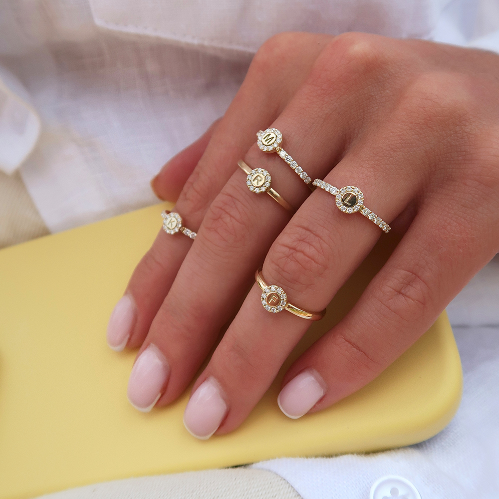 Ontwerp je eigen Initiaal Ring Halo, een verfijnde aanschuifring van 14 karaats goud met in het midden jouw gekozen initiaal of symbool, omlijst door een fonkelende halo van pav&eacute; gezette diamanten. Kies een letter die je dierbaar is, van jezelf of van een geliefde, of draag een symbool met persoonlijke betekenis. Zo draag je altijd iets kostbaars dicht bij je.