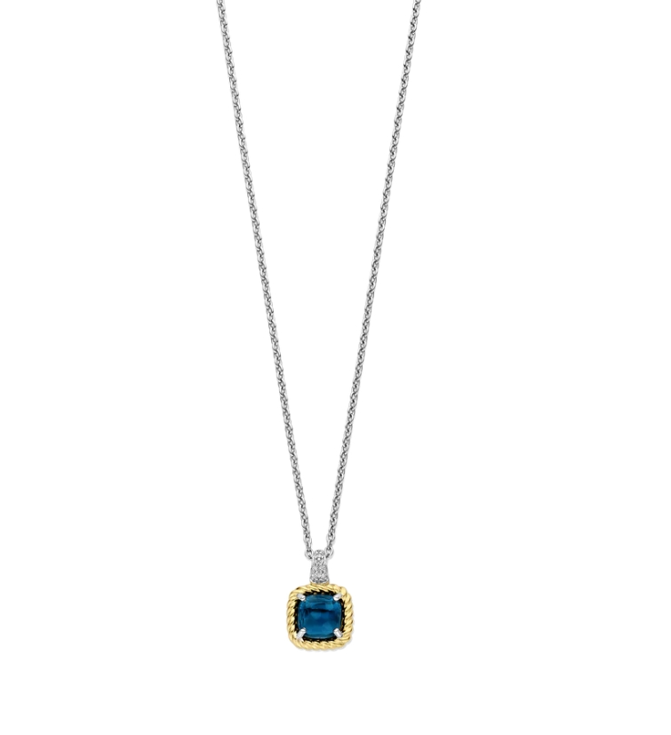 Verhef je look met dit TI SENTO vergulde collier 34111DB. Een diepblauwe kussengeslepen steen vormt het middelpunt, omlijst door een gedraaide goudkleurige randzetting die vintage elegantie oproept. De hanger hangt aan een platinakleurig vergulde houder, met de hand gezet met witte zirconia, die een delicate fonkeling toevoegt aan het gedurfde middelpunt. Vervaardigd uit hoogwaardig 925 sterling zilver speelt dit ontwerp met kleur, textuur en vorm, waarbij de rijkdom van goudkleurige accenten in balans wordt gebracht met de heldere precisie van pavé details. Het kussenvormige silhouet biedt tijdloze charme met een moderne, sculpturale twist. Combineer het met een klassieke blouse, een avondjurk of strak tailoring, dit sieraad maakt moeiteloos de overgang van dag naar nacht. Alleen gedragen zorgt het voor impact, gecombineerd met verfijnde colliers geeft het een persoonlijke touch aan je look. Nikkelvrij en hypoallergeen, het belooft zowel comfort als blijvende elegantie.