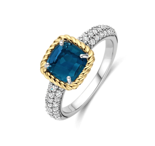 Voeg een gedurfde kleuraccent toe met deze TI SENTO vergulde ring 12399DB. Vervaardigd uit 925 sterling zilver is dit opvallende ontwerp voorzien van een kussengeslepen transparante donkerblauwe steen, gezet in een gedraaide goudkleurige klauwzetting die een sculpturale, vintage-geïnspireerde touch geeft. De platinakleurig vergulde band is pavé gezet met briljant geslepen witte zirconia en creëert een verfijnd contrast van tint en textuur. De diepe kleur en verfijnde details maken dit een uitgesproken sieraad, perfect wanneer alleen gedragen of gecombineerd voor een zorgvuldig samengestelde look. Nikkelvrij en hypoallergeen, hij biedt de hele dag comfort met tijdloze verfijning.