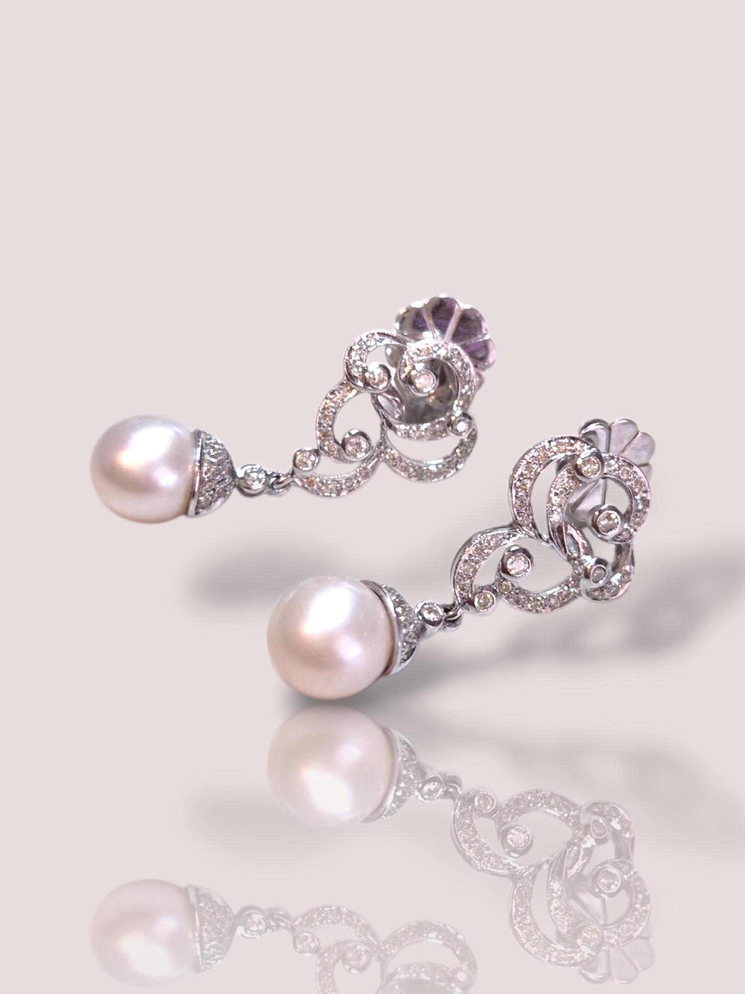 Deze vintage 18k witgouden parel oorbellen met diamanten stralen elegantie en klasse uit. De parels en diamanten vormen een tijdloos en verfijnd ontwerp dat perfect past bij elke gelegenheid. Draag deze oorbellen met een chique avondjurk voor een extra dosis glamour of met een casual outfit voor een subtiele touch van luxe. Deze oorbellen zijn een onmisbaar accessoire voor elke moderne vrouw.

De oorbellen zijn 3,8 cm lang en hebben een parel met een diameter van 1 cm. Elke oorbel bevat 41 diamanten.