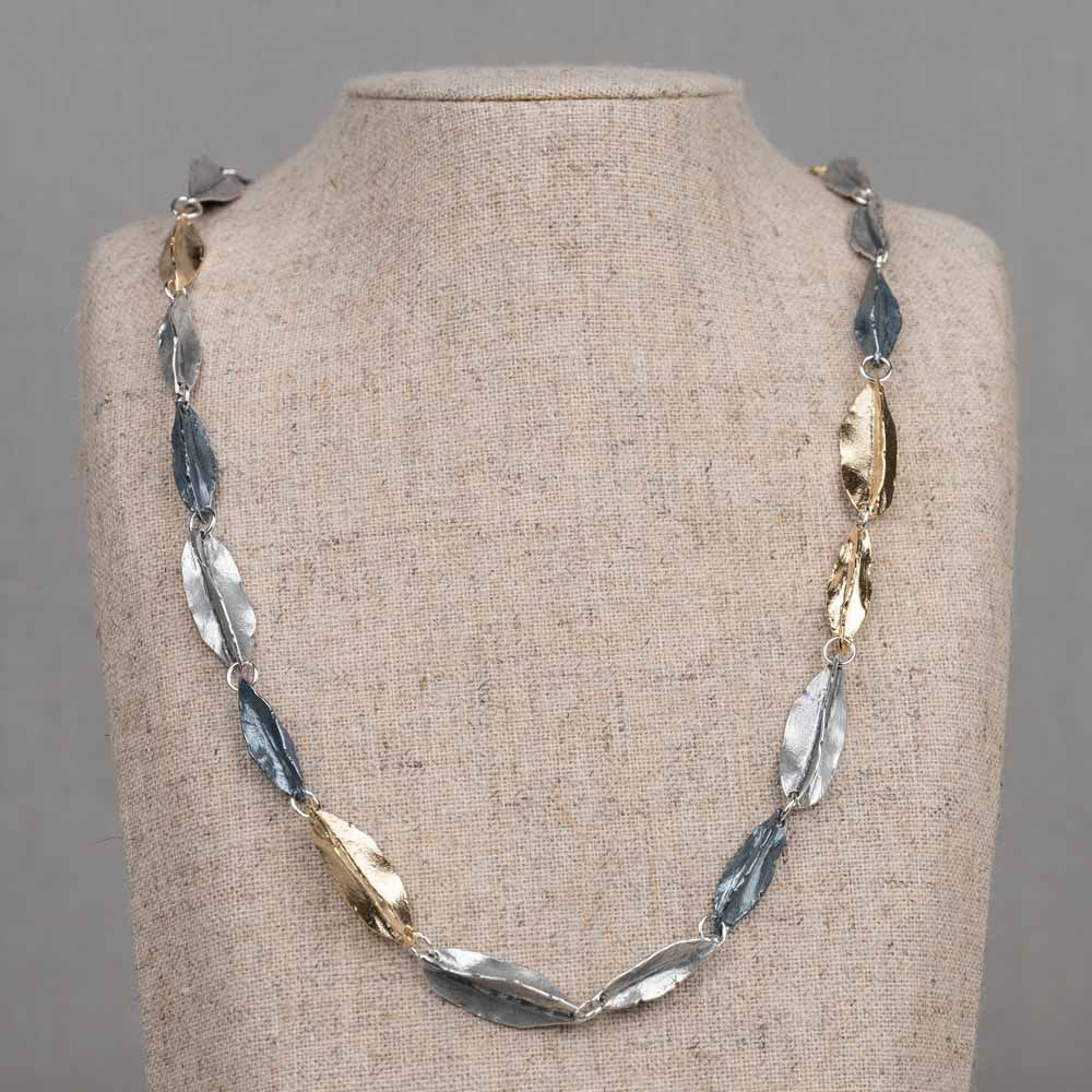 Collier met gevouwen blaadjes, gemaakt van 925 (geoxideerd) sterling zilver en zilver verguld. Het collier is verstelbaar waardoor u het op verschillende lengtes kunt dragen.
