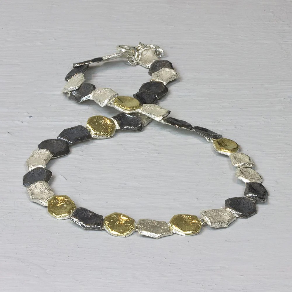 Een bijzonder collier met drie kleuren keitjes, zilver verguld, zilver en geoxideerd zilver.