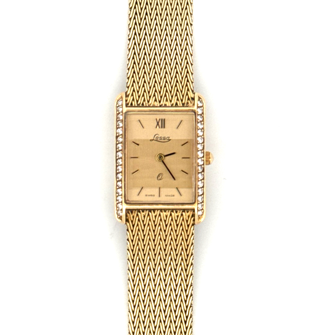 De Lessa Horloge 14krt Geelgoud met Briljanten, is een verfijnd polshorloge met een rechthoekige gouden kast en diamantdetails. Uitgerust met een Zwitserse quartz-beweging, saffierglas en een Milanese meshband van echt goud, straalt het luxe uit. Ideaal voor formele gelegenheden, waar goud en elegantie de show stelen. Geen datumfunctie.