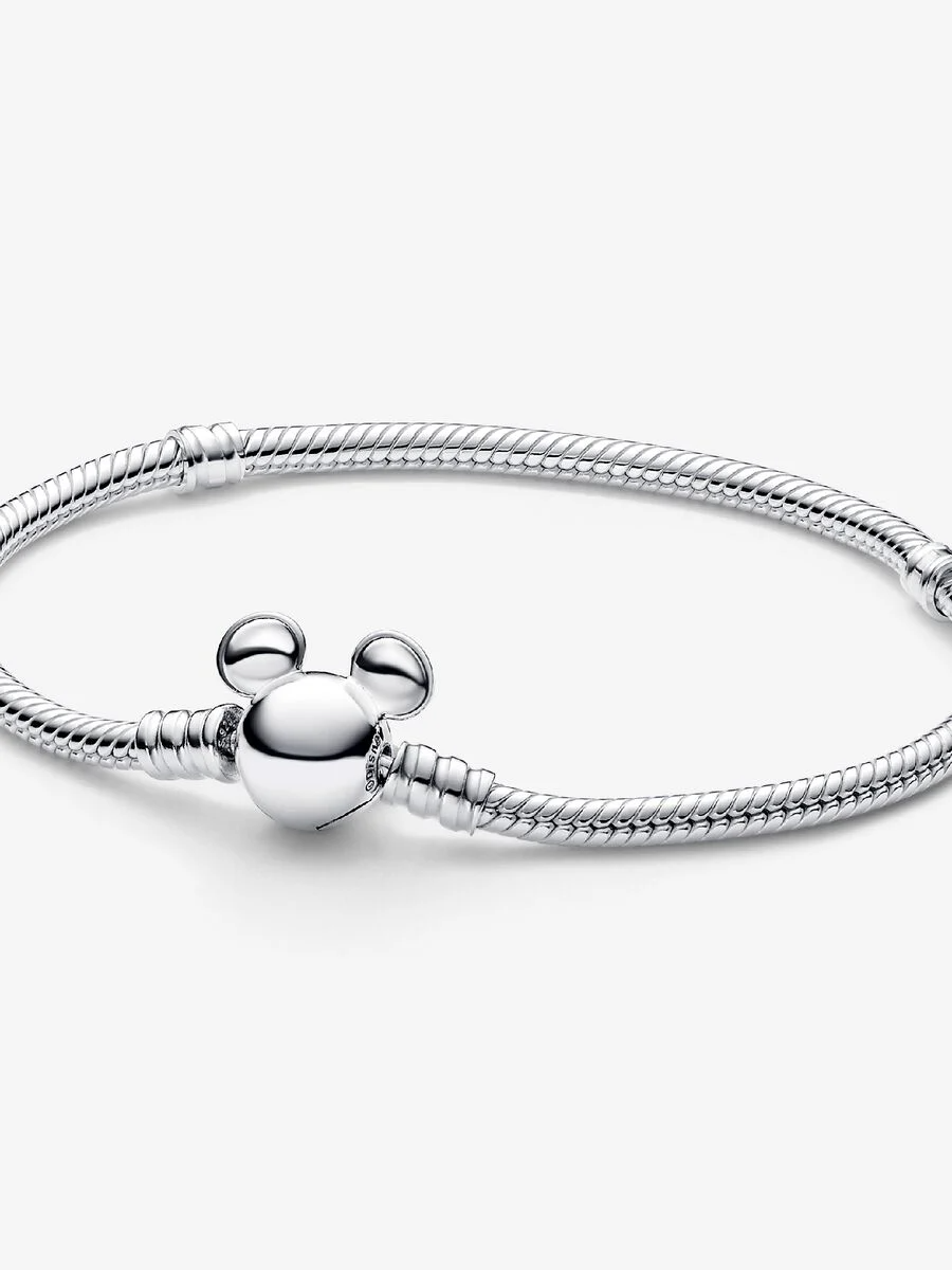 Style je Disney x Pandora bedelcollectie aan de Disney slangenschakelarmband met Mickey Mouse-sluiting van Pandora Moments Deze sterlingzilveren slangenschakelarmband heeft een sluiting ge&iuml;nspireerd op het iconische silhouet van het hoofd van Mickey Mouse. Druk de oren van Mickey in tegengestelde richtingen om de sluiting gemakkelijk te openen en te sluiten. De armband heeft twee schroefdraden (verhoogde bedelverdelers) en kan 16-18 bedels of hangende bedels dragen. De perfecte manier om je Disney-favorieten te laten zien.