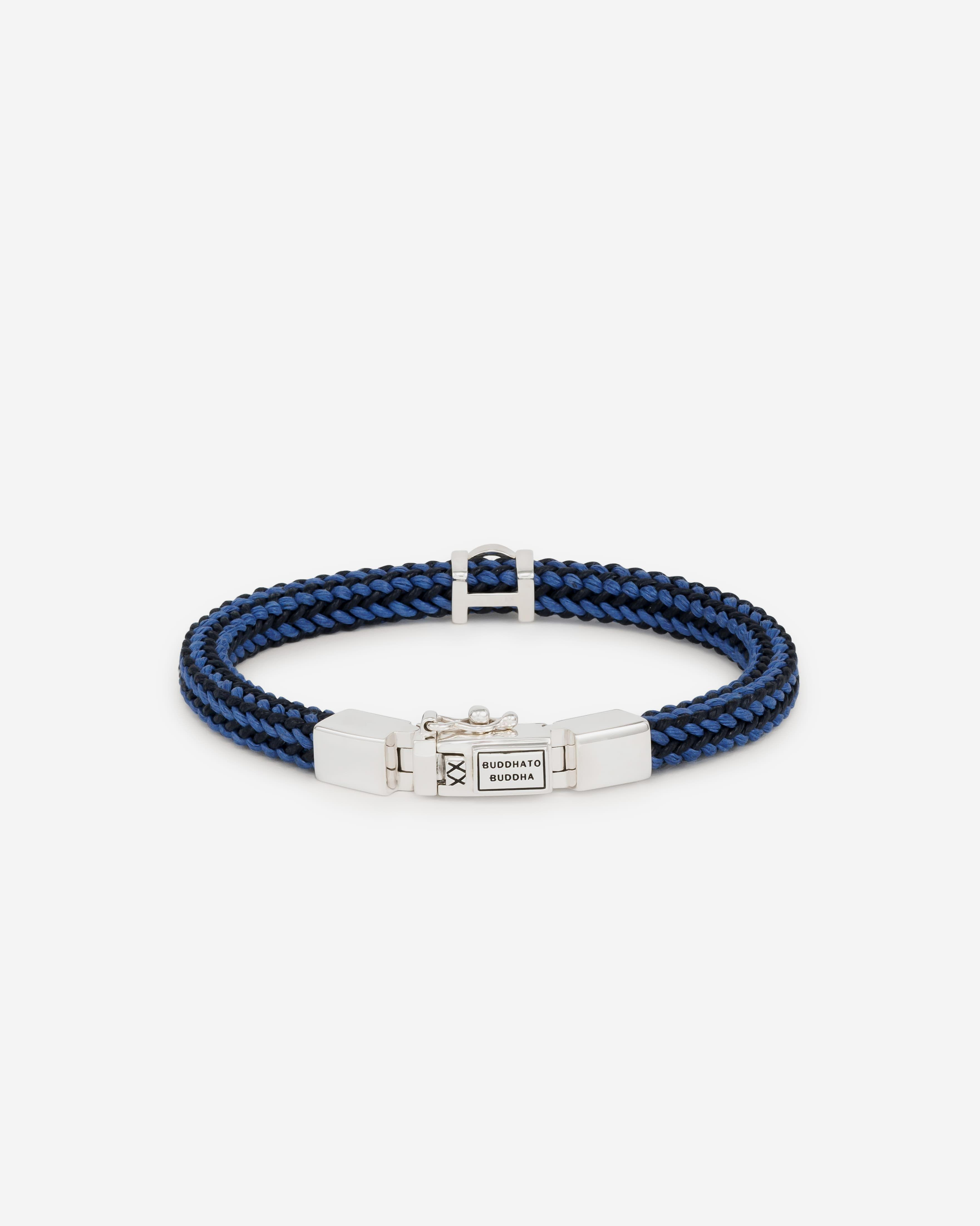 De Denise Koord Mix Blauw Armband is een stijlvol geweven koord met ons iconische en tijdloze sterling zilveren slot. Ontworpen in Amsterdam en met zorg handgemaakt in Zuidoost-Azië, voegt deze blauw met zwarte armband een stoere touch toe aan elke outfit. Combineer het met andere zilveren sieraden of draag het naast je horloge voor een complete look. Welk bijzonder verhaal vertel jij met deze armband? Let op: het is belangrijk om contact met water en langdurige blootstelling aan direct zonlicht te vermijden, om de kwaliteit van het geweven koord te behouden.