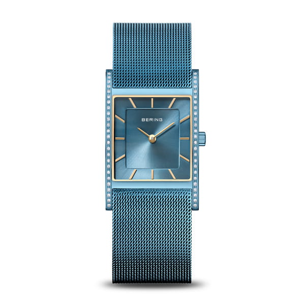  Dit rechthoekige dameshorloge van BERING combineert Scandinavisch minimalisme met een luxueuze aandacht voor detail. De gepolijste roestvrijstalen kast in een diepe, stralende blauwe kleur trekt de aandacht met een verfijnde omlijsting van fonkelende zirkonia-steentjes &ndash; een subtiele schittering die doet denken aan het spel van licht op Arctisch ijs. De diepblauwe sunray-wijzerplaat geeft het horloge een elegante diepte en verandert van tint afhankelijk van het licht, geaccentueerd door goudkleurige indexen en wijzers die het ontwerp een warme elegantie meegeven.