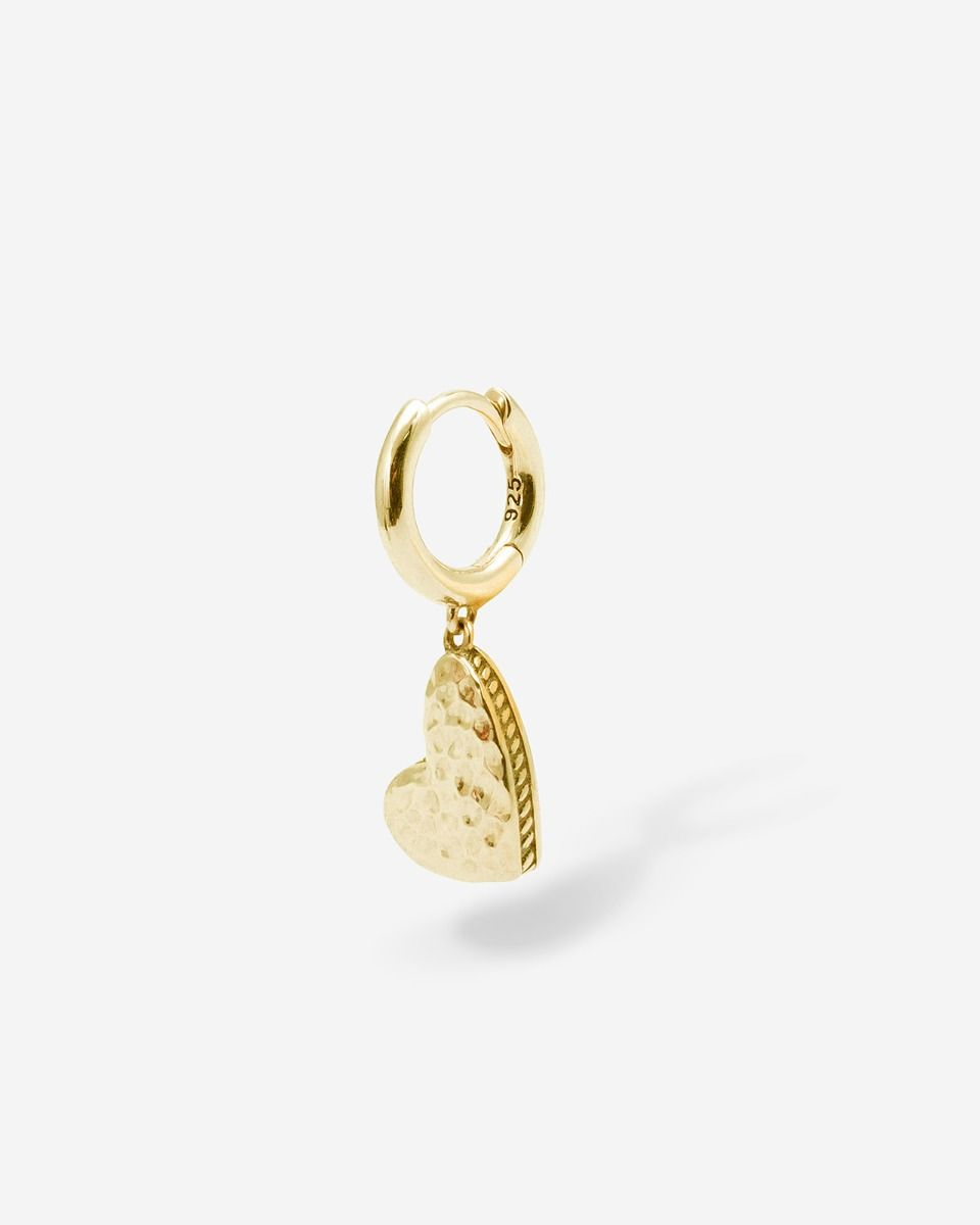Delicaat en toch vol betekenis; onze Heart Hoop Oorbel in Goud Vermeil is romantisch, met een rebelse twist. Het is het perfecte sieraad voor de trendsetters, de risiconemers en de rebellen. Een klassiek ringetje met een sierlijke bedel verbindt de drager op eenvoudige, maar diepgaande wijze met een geliefde. Het oppervlak is met de hand gehamerd en maakt elke oorbel one of a kind, voor een unieke look met een rauw randje. Ontworpen in Amsterdam en handgemaakt in Zuid-Oost Azi&euml; van gerecycled zilver met een premium gold plating (3.0 micron dik). De plating is gemiddeld 5 maal dikker dan reguliere gold plated items. Kun jij je het onoverwinnelijke gevoel van liefde voorstellen bij het dragen van dit handgemaakte aandenken?