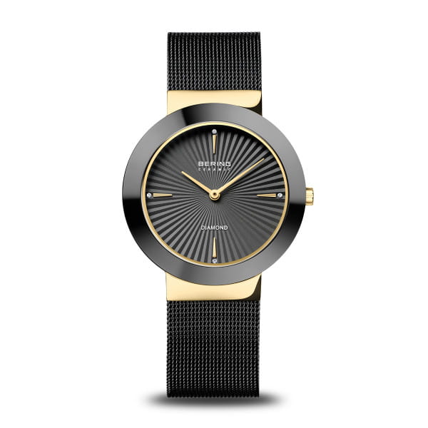  Dit luxe dameshorloge combineert een minimalistisch design met een verfijnde mix van materialen. De gepolijste roestvrijstalen kast met goudkleurige PVD-coating wordt omlijst door een diepzwarte, hoogglans keramische lunette. De fijne zwarte Milanese band met veilige vouwsluiting vult de elegante uitstraling perfect aan en biedt optimaal draagcomfort.  De antracietkleurige wijzerplaat heeft een zonnestraalpatroon dat het licht in levendige reflecties weerkaatst. Vier echte diamanten markeren subtiel de uren op 12, 3, 6 en 9 uur. Het platte saffierglas biedt langdurige bescherming tegen krassen en behoudt de onberispelijke uitstraling van het horloge.  Met een breedte van 35 mm, een lengte van 38 mm en slechts 6 mm dik draagt dit horloge licht en comfortabel. Een nauwkeurig quartz uurwerk zorgt voor betrouwbare tijdweergave, terwijl de waterdichtheid tot 5 ATM het geschikt maakt voor dagelijks gebruik.  Een harmonieuze combinatie van keramiek, roestvrij staal, goud en diamanten &ndash; ontworpen voor vrouwen die tijdloze schoonheid en luxueuze details waarderen. 