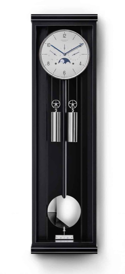 Erwin Sattler Classica KS 100 M. Leverbaar in zwart gelakt met metaal inleg of zwart gelakt met een Macasar achterwand. Uurwerk Kaliber 1575. Loopduur 30 dagen. Metalen wijzerplaat met handbeschilderde maanstand en dag- en datum aanduiding. Uurwerk met 15 robijn lagers en 8 precisie kogellagers. Gongslag op halve en hele uren. Hand bewerkte geblauwd stalen wijzers. Slingerlens en lunette massief vernikkelt.