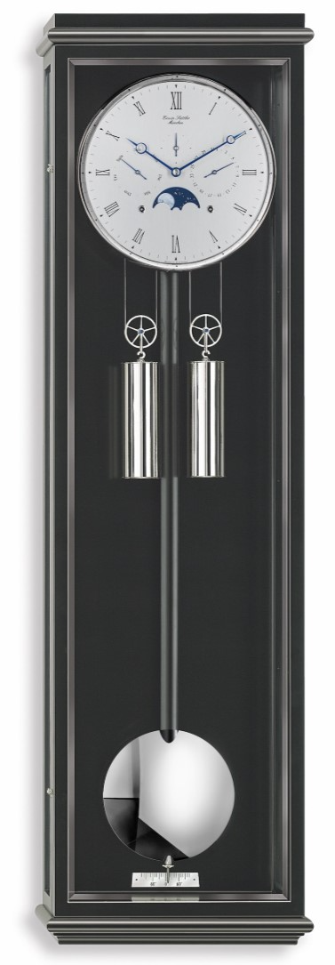 Erwin Sattler Classica KS 100. Leverbaar in zwart gelakt met facette geslepen glas. Uurwerk Kaliber 1575. Loopduur 30 dagen. Metalen wijzerplaat met handbeschilderde maanstand en dag- en datum aanduiding. Uurwerk met 15 robijn lagers en 8 precisie kogellagers. Gongslag op halve en hele uren. Hand bewerkte geblauwd stalen wijzers. Slingerlens en lunette massief vernikkelt.