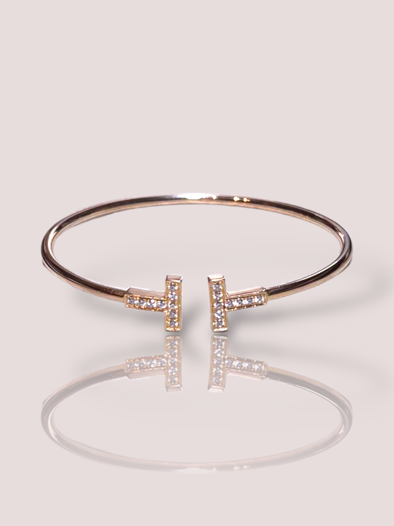 Deze Vintage 18k rosé gouden T Wire Tiffany & Co armband,  is een verfijnd sieraad en een van de klassieke modellen van Tiffany. Draag deze elegante armband solo voor een minimalistische look of combineer met andere armbanden voor een trendy, gelaagd effect. Perfect voor dagelijks gebruik of speciale gelegenheden. Een tijdloze toevoeging aan je sieradencollectie.

De armband is geschikt voor een polsmaat 16 of 17. De T's zijn elk bezet met 9 briljant geslepen diamanten, in totaal tezamen 0,24ct.