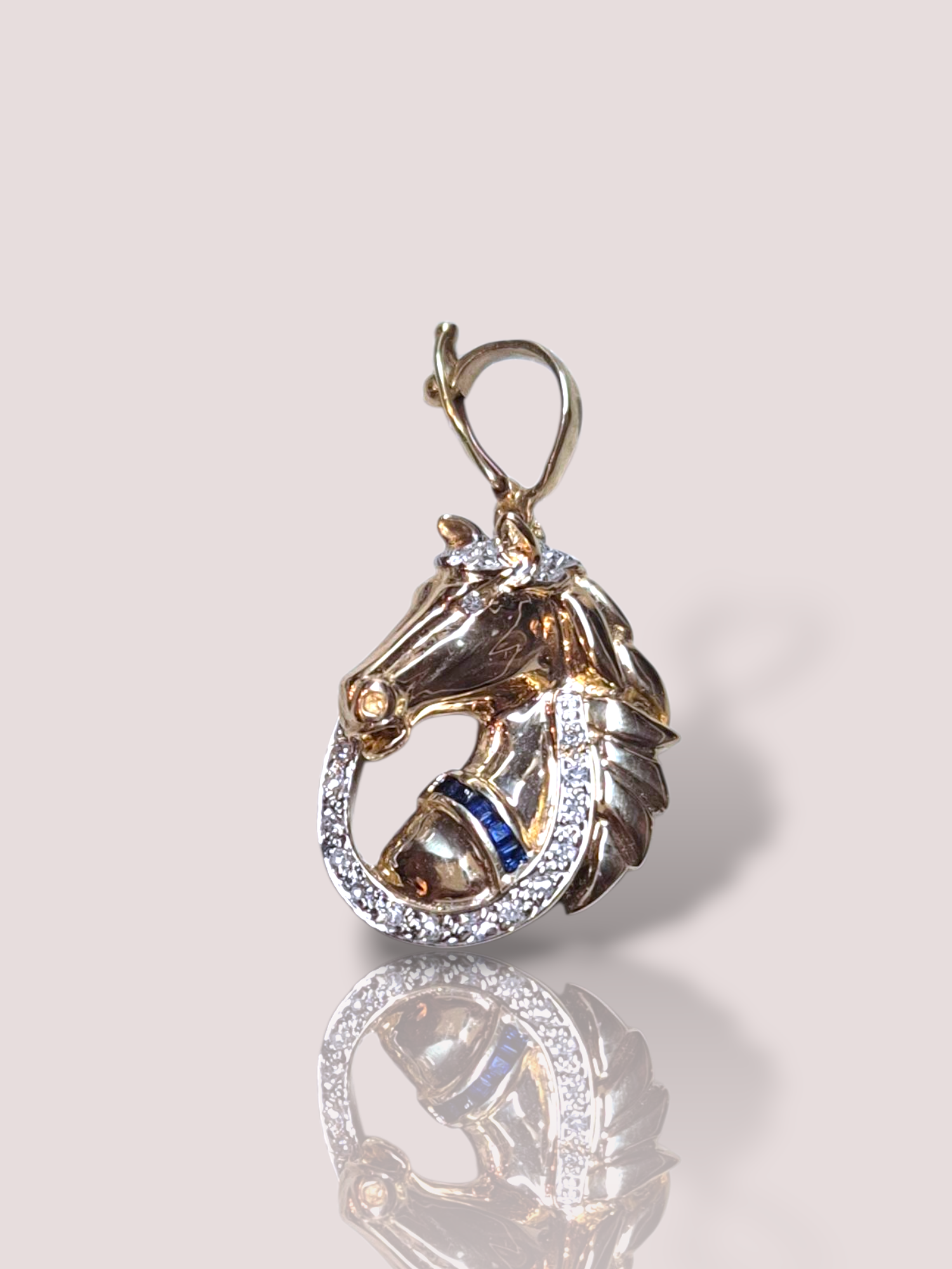 De vintage 14k geelgouden paardhanger met diamanten is een prachtig sieraad in de categorie juwelen, type hanger, subtype briljante hangers. Draag deze elegante hanger aan een fijne ketting om de hals, perfect om zowel alledaagse als speciale gelegenheden een stijlvolle touch te geven. Een tijdloos stuk voor elke sieradenverzameling.

De hanger heeft een hoogte van 2,5 cm en is 2 cm breed. De hanger weegt 5,65 gram en bevat 5 princess cut saffieren en 24 diamanten van tezamen 0,31ct.