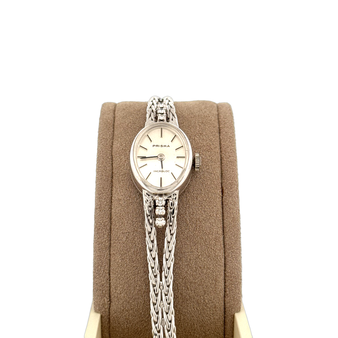 De Prisma Horloge 14krt Witgoud met Briljanten is een luxe horloge met een zilverkleurige 14-karaats gouden horlogeband en kast. Het beschikt niet over een datumaanduiding. Draag dit verfijnde horloge tijdens formele gelegenheden of combineer het met elegante, chique outfits voor een verfijnde uitstraling. Perfect voor degenen die houden van tijdloze luxe.