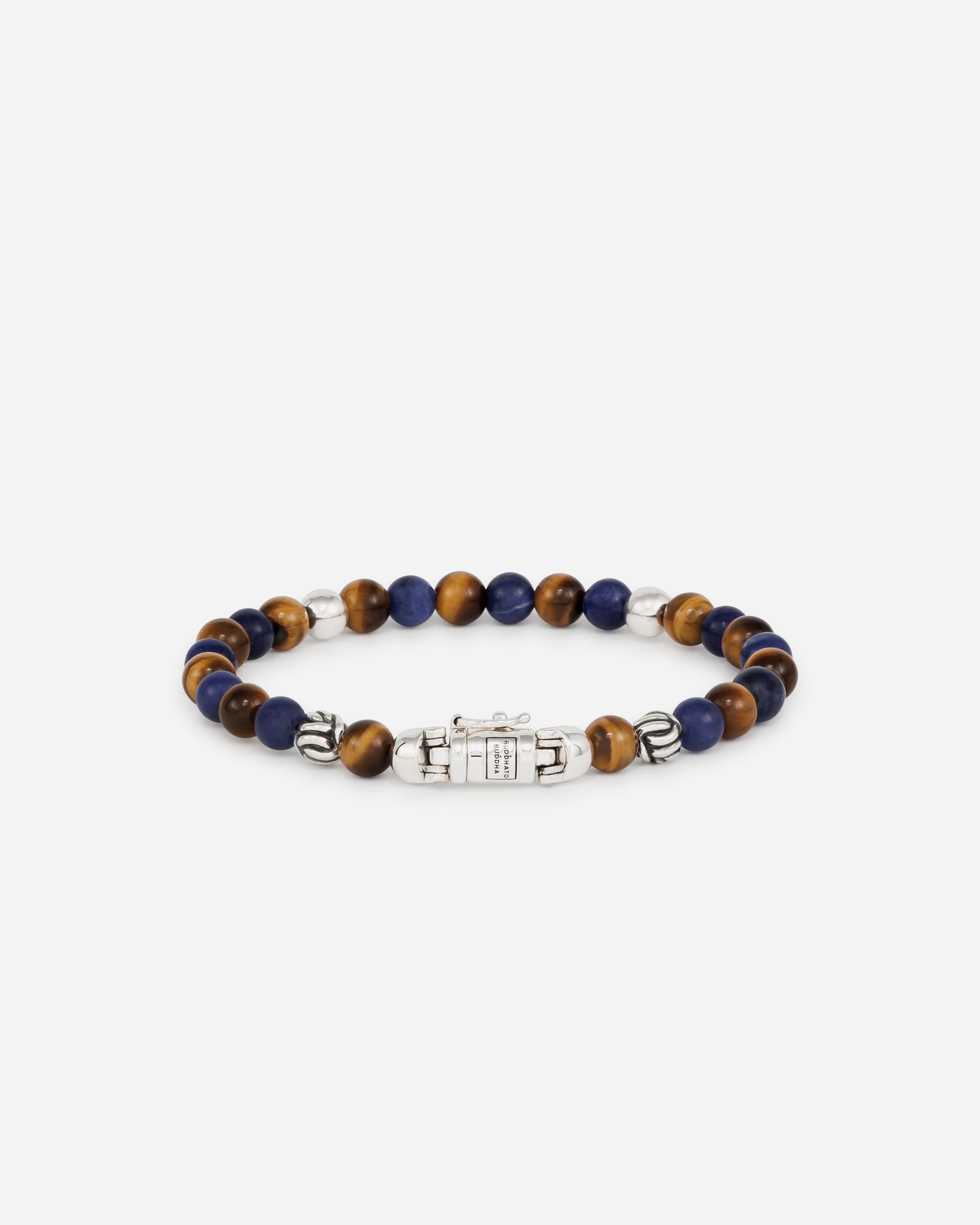 De Spirit BeadMini Mix Sodalite Tijgeroog Armband, geïnspireerd op bidkralen, is een prachtig Buddha to Buddha ontwerp met het herkenbare sterling zilveren slot. De armband bevat afwisselend sodaliet- en tijgeroogstenen. De mini-spirit kralen zijn kleiner dan de spirit bead armbanden. Sodaliet bevordert expressie, terwijl tijgeroog motivatie en focus stimuleert. Handgemaakt van gerecycled premium zilver en tijdloos. Kracht en esthetiek smelten samen in dit product. Handgemaakt met duurzame materialen om een leven lang mee te gaan. Let op: de sluiting van deze Spirit Bead armband bevat een magneet. Deze is niet roestvrij en daarom is het belangrijk om elk contact met water (zoals zwemmen en douchen, enz.) te vermijden om roestvorming rond de magneet te voorkomen.
