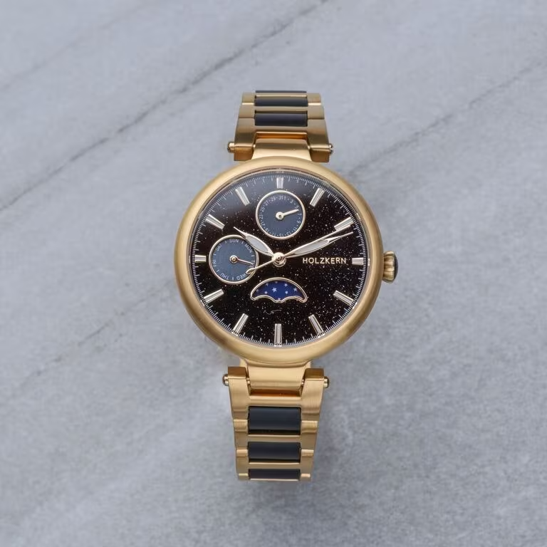 Pluk de maan uit de hemel &ndash; met je Moonbow dameshorloge met maanfaseweergave.

De hemel is donker, de maan staat laag en werpt licht door een sluier van nevels, waardoor regenbogen ontstaan ​​&ndash; zo zeldzaam als vallende sterren aan de winterhemel, zo ongelooflijk als sneeuwkristallen in het zomerlicht.

Met zwarte aventurijn, esdoorn en parelmoer legt je Moonbow dit moment perfect vast. De maanfaseweergave toont de reis van de maan op je pols, terwijl goudkleurig roestvrij staal de schittering van de sterren vastlegt.

Een horloge vol dromen &ndash; voor iedereen die de maan als een stille vriend en bondgenoot beschouwt.