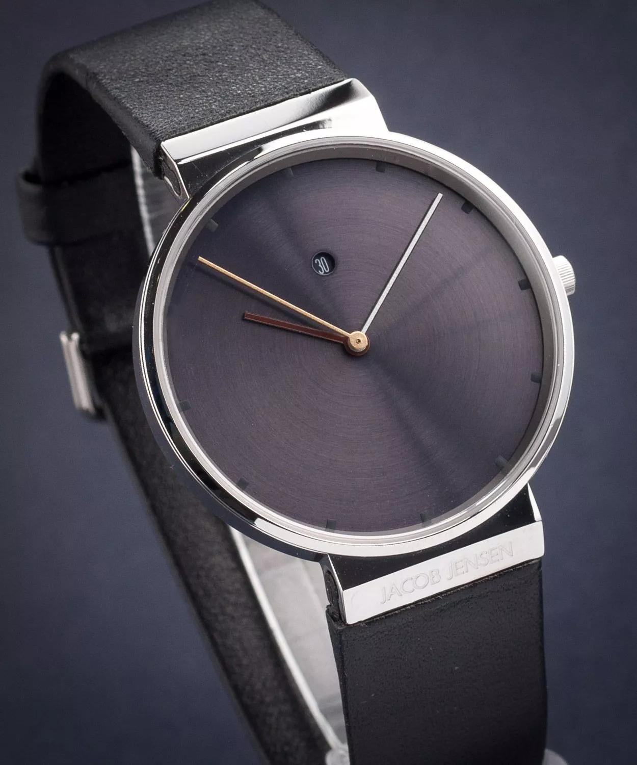 De Jacob Jensen New Line JJ841 is een dameshorloge met een zilverkleurige stalen kast en een zwarte leren band. Het horloge wordt aangedreven door een betrouwbaar Zwitsers ETA quartz-uurwerk. De tijd wordt aangegeven door subtiele gekleurde wijzers en een secondewijzer. Het horloge is voorzien van een datumaanduiding en saffierglas.