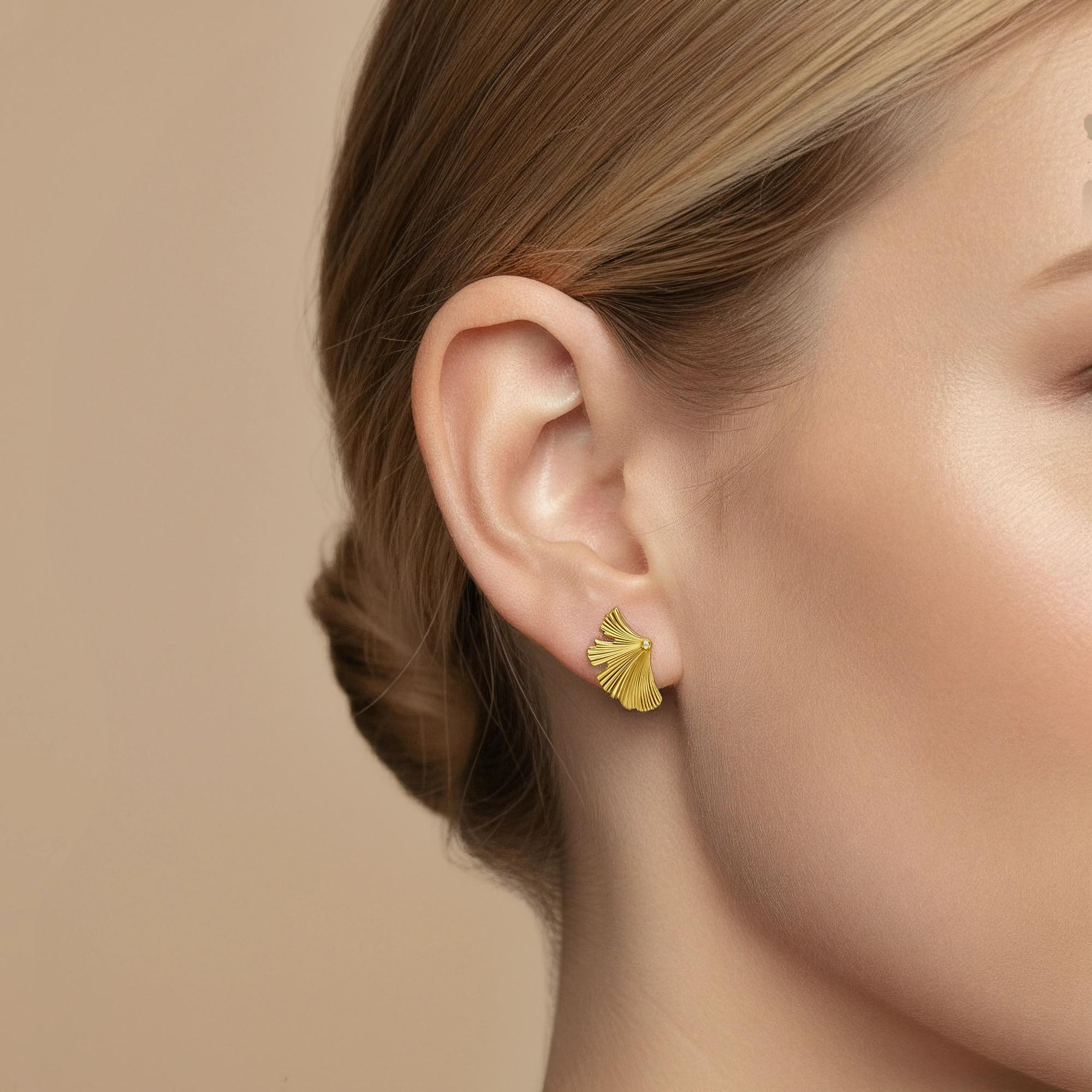 Een ode aan stille genialiteit. Deze kleine waaiervormige studs belichamen het zachte de gratie van de pluim van de pauw, die zijn tere kromming in een zacht geborstelde vorm vastlegt Fins. Een enkele diamant nestelt zich aan de rand, als het oog van de veer &mdash; een subtiele knik naar helderheid, wijsheid en innerlijke kracht. Ingetogen maar stralend, Ze zijn het perfecte alledaagse symbool van gracieuze zelfverzekerdheid.