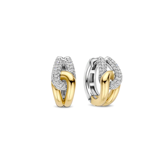 Stap in de spotlight met deze sculpturale TI SENTO vergulde oorbellen 78033ZY. Vervaardigd uit 925 sterling zilver, wikkelen ze zich om het oor in een gedurfde draai van contrast en schittering. De ene zijde is goudkleurig verguld, terwijl de andere zijde platinakleurig verguld is en bezet met twee gebogen rijen briljant geslepen witte zirconia. Het verstrengelde ontwerp vangt het licht vanuit elke hoek en zorgt voor een perfecte balans tussen textuur, fonkeling en verfijning. Nikkelvrij en hypoallergeen, deze oorbellen zijn gemaakt voor luxe die de hele dag door gedragen kan worden, met een zelfverzekerde uitstraling.