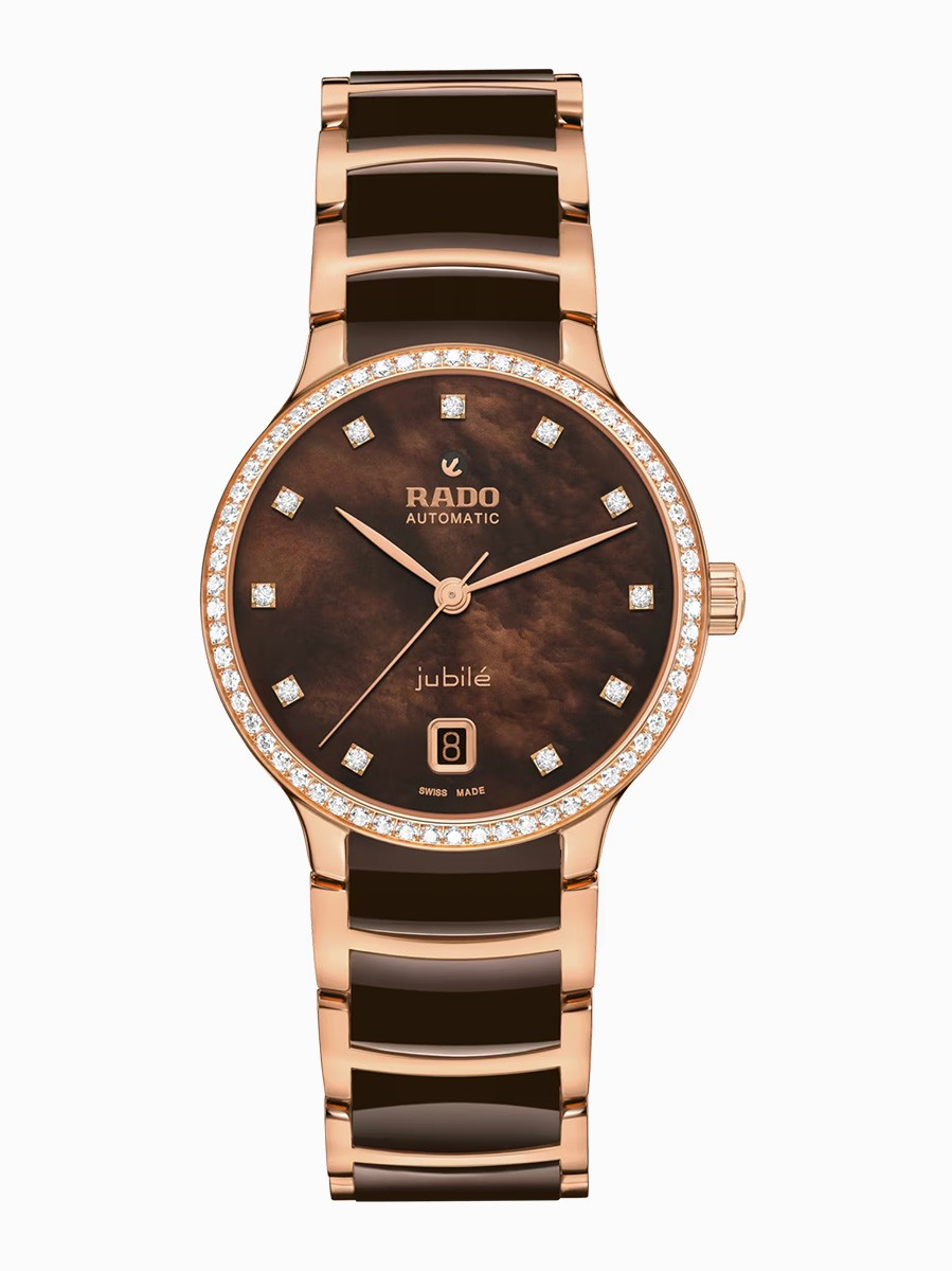 Ervaar de harmonieuze mix van artistieke expressie en verfijnd design met de Centrix Super Jubil&eacute;. De 35 mm kast, vervaardigd uit roestvrij staal en voorzien van een ros&eacute;gouden PVD-coating, wordt bekroond door een ros&eacute;gouden PVD-gecoate roestvrijstalen lunette bezet met 60 Top Wesselton VS-SI full-cut diamanten en een gebogen saffierglas met een antireflectiecoating aan beide zijden, voor een onberispelijke afleesbaarheid. In het hart ervan, en zichtbaar vanaf de saffierglazen achterkant, klopt het nauwkeurig afgestelde Automatic R763 kaliber, gereguleerd in vijf posities en uitgerust met een Nivachron&trade;-spiraalveer, voor uitzonderlijke nauwkeurigheid en een indrukwekkende gangreserve van 80 uur. De bruine parelmoeren wijzerplaat, versierd met 11 Top Wesselton VS-SI full-cut diamanten indexen en een datumvenster op 6 uur, straalt tijdloze elegantie uit. Het algehele uiterlijk van dit iconische horloge wordt gecompleteerd door elegant afgestelde kastaanzetten en een band van gepolijst ros&eacute;goudkleurig PVD-gecoat roestvrij staal met bruine hightech keramische middenschakels, beveiligd door een drievoudige sluiting van geborsteld roestvrij staal.