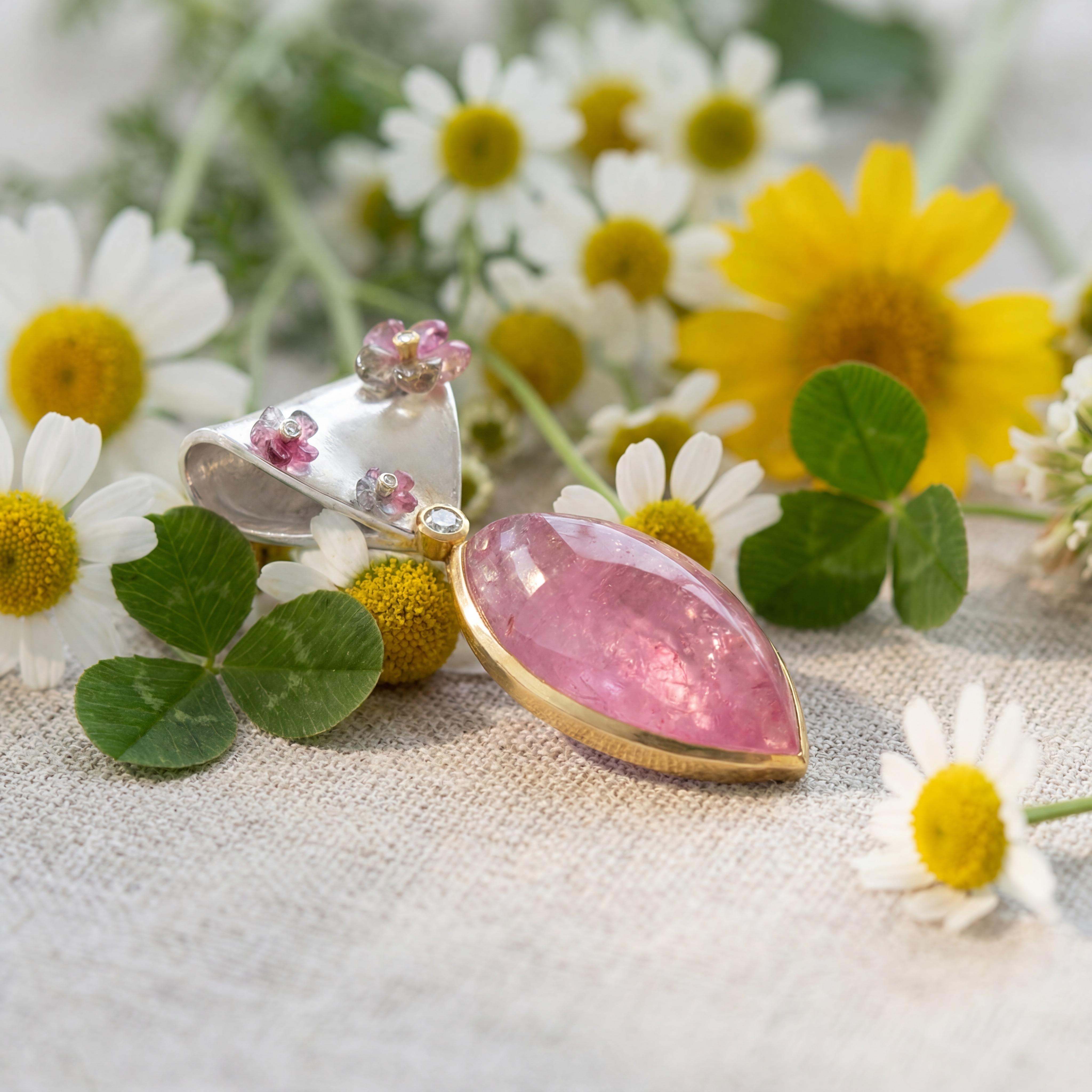Dieser Anhänger als Schlaufe aus Silber und Gold 900 gefertigt, ist mit gravierten Turmalinblüten und Brillanten besetzt. Der große rosa Turmalin mit 54,9ct besitzt ein phantastische Farbe und ist daher eine Rarität. Als elegantes Unikat passt er perfekt zu Halsketten oder Rundseilcolliers und kann sowohl zu Alltag als auch besonderen Anlässen getragen werden. 
