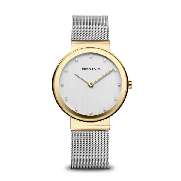  De BERING 10135-010 combineert strak minimalisme met een vleugje glamour. De glanzende goudkleurige kast vormt een elegant contrast met de zilverkleurige Milanese band &ndash; een subtiel bicolor-effect dat klasse en moderniteit uitstraalt. Op de geborstelde wijzerplaat fonkelen vier echte diamanten zachtjes in het licht.  Ge&iuml;nspireerd door de helderheid van het Noordpoolgebied, staat BERING voor tijdloze eenvoud. Met zijn ultradunne kast, krasbestendig saffierglas en betrouwbaar kwartsuurwerk is dit horloge perfect voor elke dag &ndash; en elke gelegenheid. 