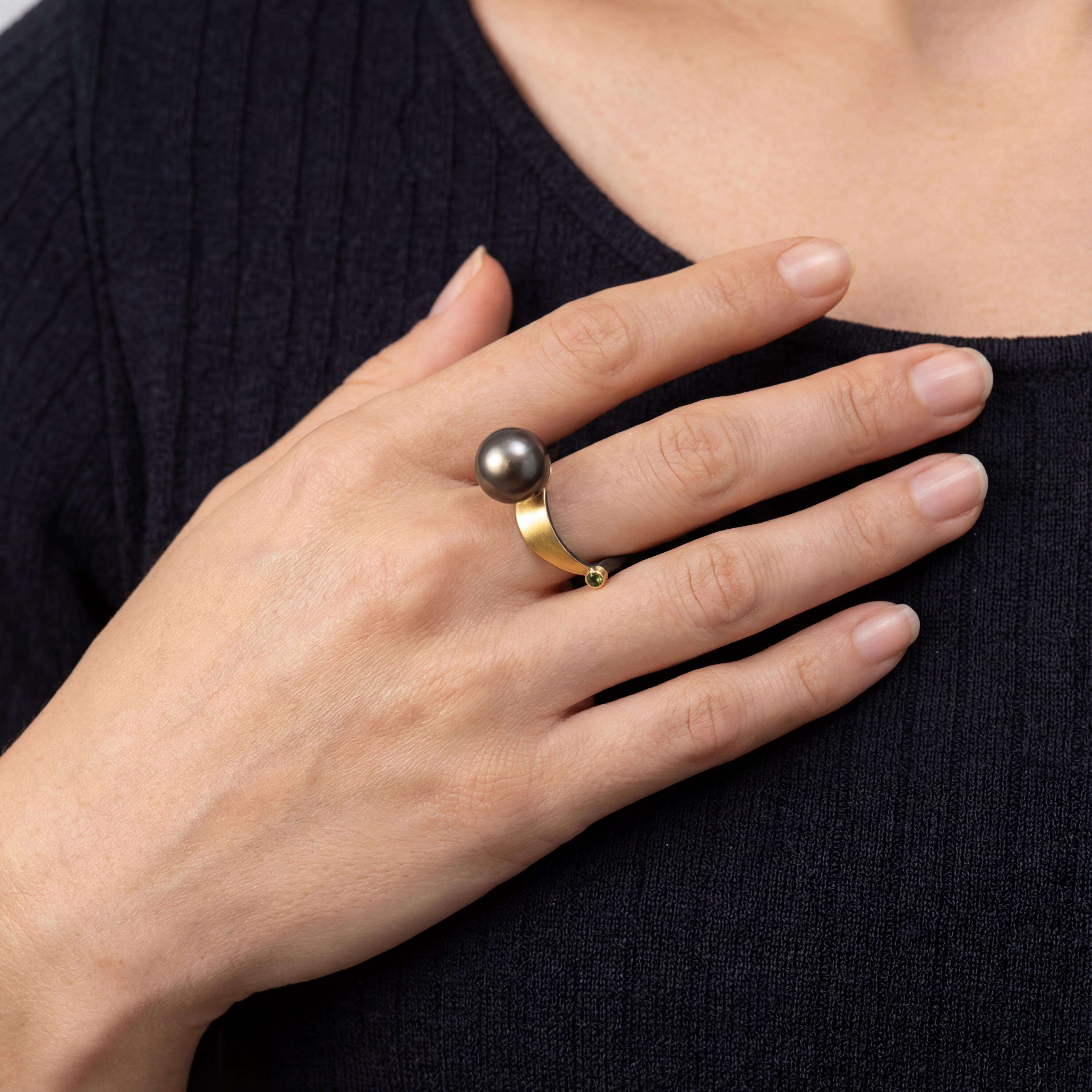 Dieser elegante Ring aus der Kategorie Schmuck besticht durch eine harmonische Kombination aus Silber (Ag) und Gold (Au), verziert mit einer Tahiti-Perle und funkelnden grünen Brillanten. Ideal für besondere Anlässe oder als stilvolles Accessoire im Alltag. Tragen Sie ihn an Ihrem Lieblingsfinger, um jedem Outfit eine luxuriöse Note zu verleihen.