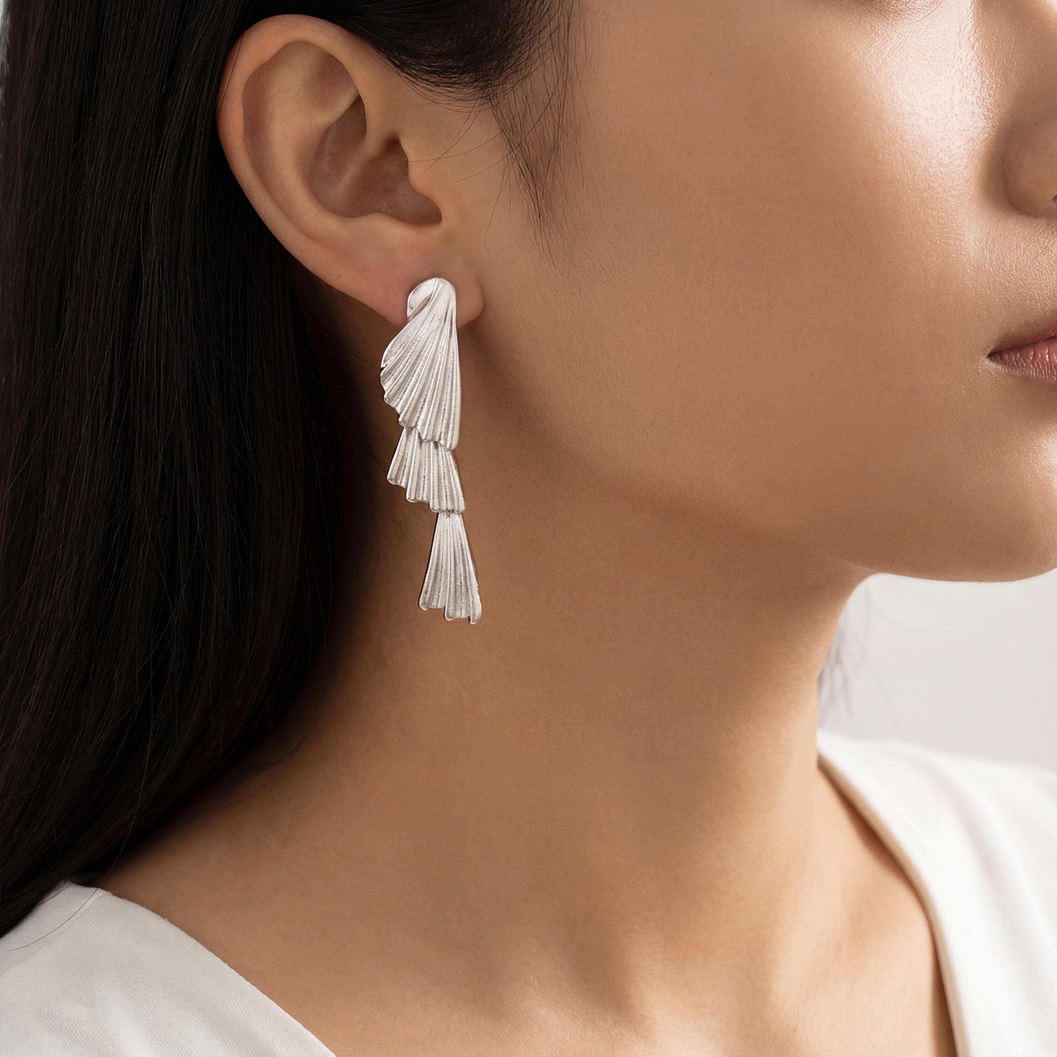 Diese Muschelohrringe in Silber sind elegante Plättchen-Ohrringe aus hochwertigem Silber. Diese zeitlose Goldschmiedearbeit passt perfekt zu formellen Anlässen oder einem stilvollen Alltagslook. Kombinieren Sie sie mit anderen silbernen Accessoires für einen harmonischen Auftritt. Ideal als dezentes Highlight zu schlichten Outfits oder als Ergänzung zu glamourösen Abendgarderoben. UNIKATE