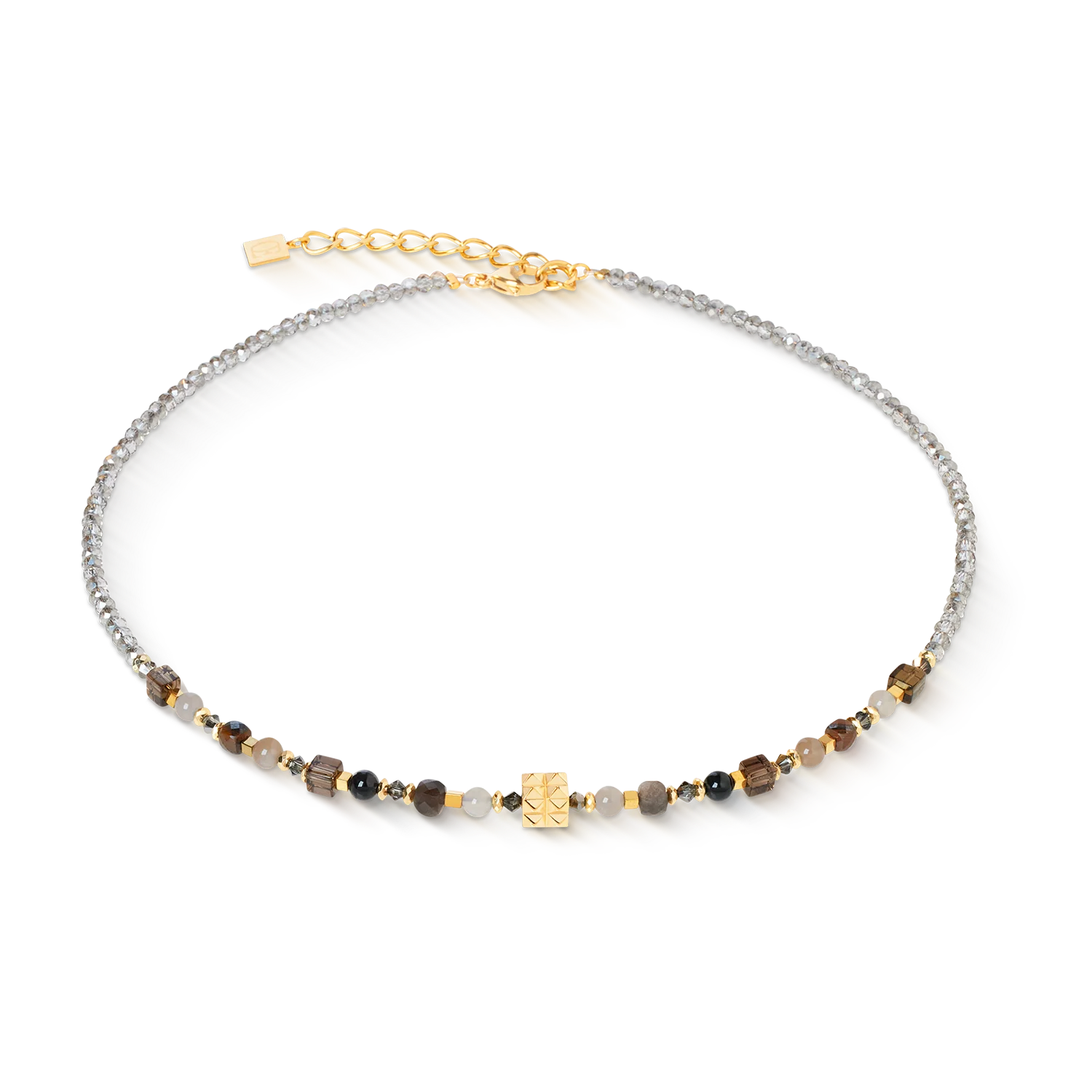 De Shape Mix Spikes Smoky Glow-ketting combineert elegante natuurlijke schoonheid met een modern design. In het midden bevindt zich een kubus met spikes van verguld roestvrij staal, geflankeerd door sprankelende Swarovski&reg;-kristallen en zorgvuldig geselecteerde edelstenen zoals rookkwarts, chocolademaansteen, gestreepte onyx, agaat en tijgeroog. Het warme kleurenpalet met rokerige en goudbruine nuances geeft de ketting een elegante diepte die perfect past bij uiteenlopende outfits. Een expressief sieraad, handgemaakt in Duitsland.