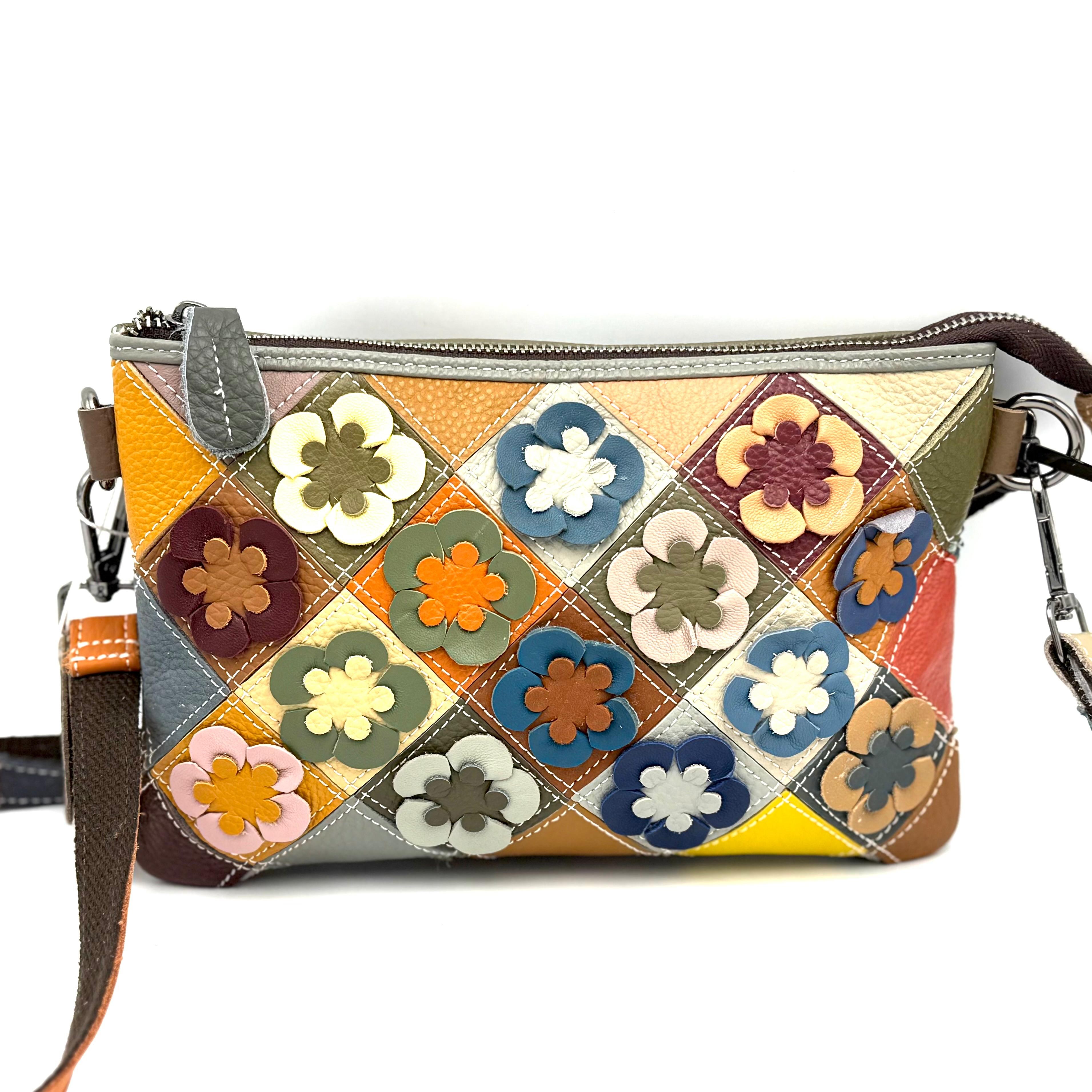 Kleurrijke tas &ndash; gemaakt in Itali&euml;
Deze compacte tas heeft &eacute;&eacute;n hoofdvak en is voorzien van een verstelbare en afneembare schouderriem &eacute;n een korte afneembare polsband, waardoor je hem op verschillende manieren kunt dragen. De voorkant is versierd met een opgestikt bloemmotief, terwijl de achterkant een patchworkdesign met ritsvak heeft.

De binnenkant is praktisch ingericht met &eacute;&eacute;n vak, inclusief een ritsvak en vakjes voor je telefoon. De tas is uitgevoerd in vrolijke kleuren en perfect voor dagelijks gebruik of een dagje uit.

Specificaties:

Aantal vakken: 1 hoofdvak

Schouderriem: verstelbaar en afneembaar

Extra: korte afneembare polsband

Voorzijde: opgestikt bloemmotief

Achterzijde: patchwork met ritsvak

Binnenkant:

1 ritsvak

telefoonvakjes

Kleur: meerkleurig

Herkomst: gemaakt in Itali&euml;

Afmetingen:

Hoogte: 17 cm

Breedte: 25 cm

Diepte: 5 cm