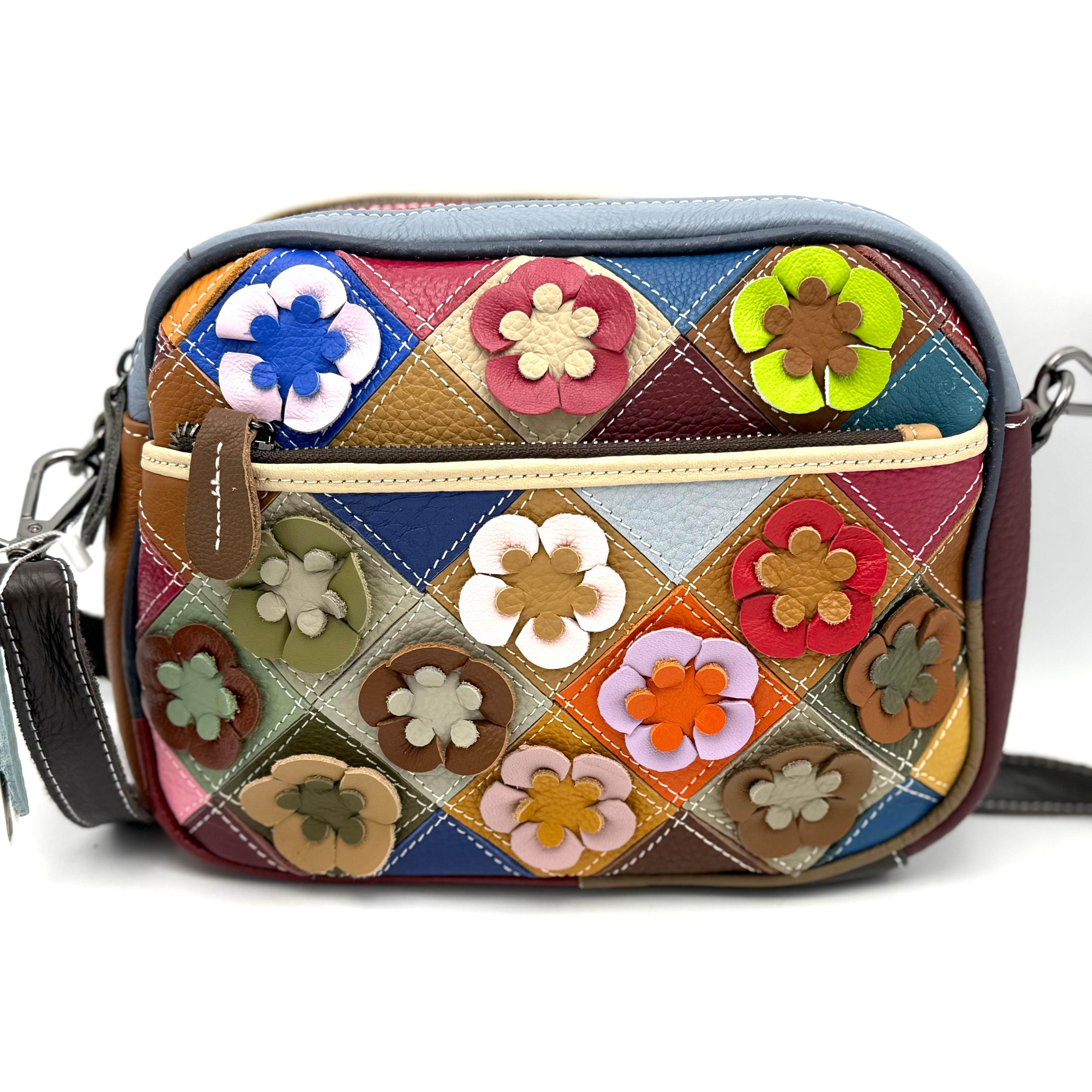 Vrolijk gekleurde tas met een speels en uniek design. De voorkant is rijk versierd met opgestikte, kleurige bloemen die de tas een vrolijke uitstraling geven. De achterkant heeft een rustig, glad patchwork motief voor een mooi contrast.

De tas beschikt over twee topritsen en is voorzien van zowel een voorrits als een achterrits. Dankzij de verstelbare en afneembare schouderriem is de tas comfortabel te dragen op verschillende manieren. Binnenin vind je een ritsvak en een apart telefoonvak, zodat al je essentials overzichtelijk opgeborgen zijn. Compact, maar zeer praktisch voor dagelijks gebruik.

Specificaties:

Design: opgestikte kleurige bloemen (voorzijde), glad patchwork motief (achterzijde)

Kleuren: vrolijke kleuren

Draagopties: twee

Sluitingen: voorrits en achterrits

Schouderriem: verstelbaar en afneembaar

Binnenkant: ritsvak en telefoonvak

Afmetingen:

Hoogte: 18 cm

Breedte: 25 cm

Diepte: 9 cm