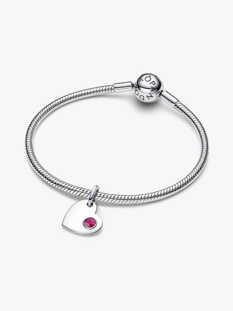 De Pandora Juli Graveerbare Hart Echt Rode Steen Hangende Bedel, modelnummer 794295C07, bevat een glinsterende rode steen en kan worden gegraveerd voor een persoonlijke touch. Het is perfect om te dragen aan een Pandora-armband of ketting voor een persoonlijke en elegante look. Voeg het toe aan je collectie voor een unieke stijl.