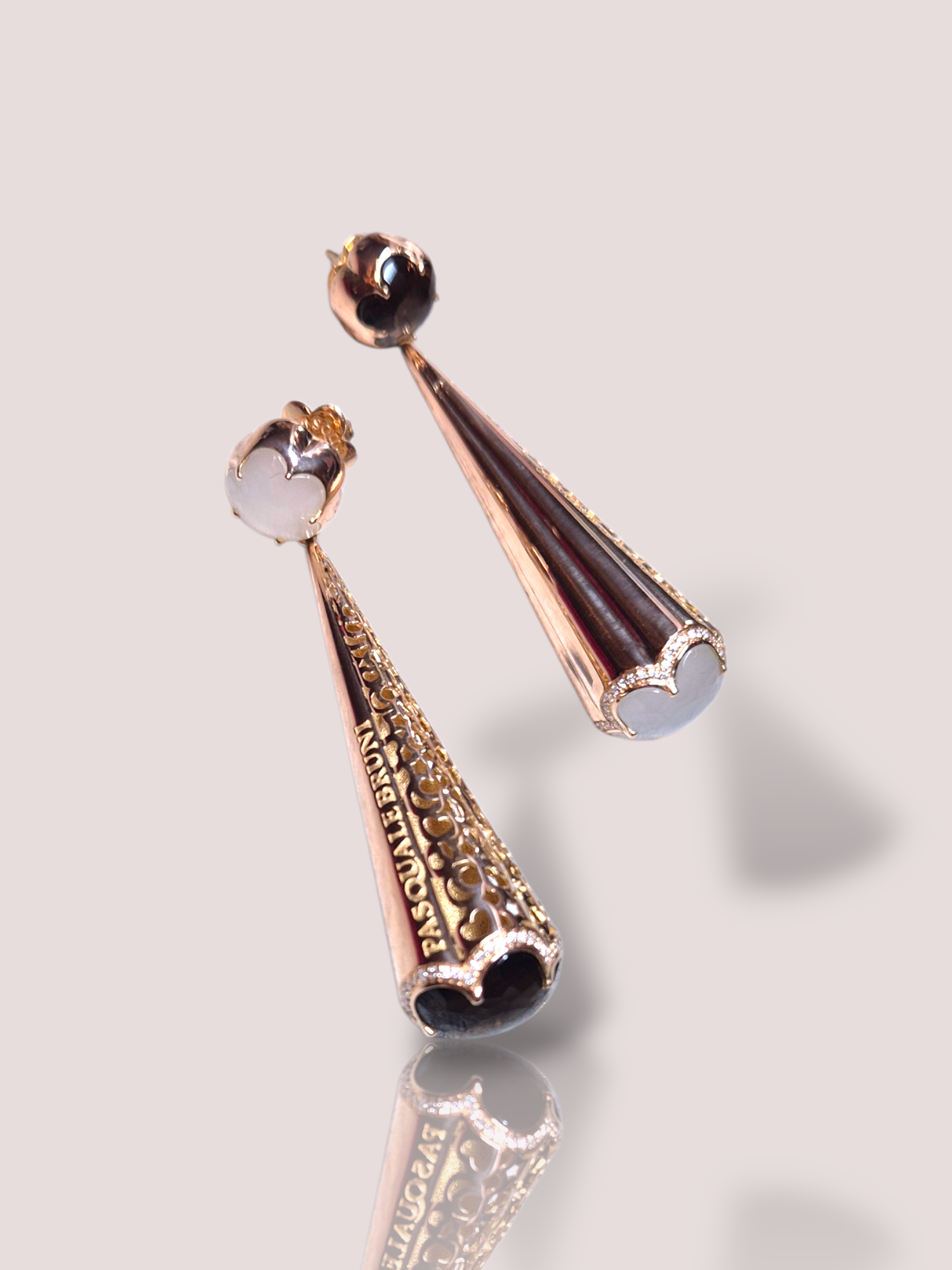 Deze prachtige Vintage 18k ros&eacute;gouden oorbellen van Pasquale Bruni, combineren elegantie met unieke elementen zoals rookkwarts en maansteen. Daarnaast bevatten de onderkantjes van de oorbellen ook nog prachtige witte diamanten. Draag ze bij een chique avondoutfit of een formele gelegenheid voor een verfijnde uitstraling. Combineer met een opgestoken kapsel om de oorbellen volledig te laten schitteren.

De oorbellen zijn 6,8 cm lang en hangen prachtig langs het gezicht. Ze bevatten 118 diamantjes van circa 0,005ct. In totaal bevatten de oorbellen  samen circa 0,60ct aan diamant.