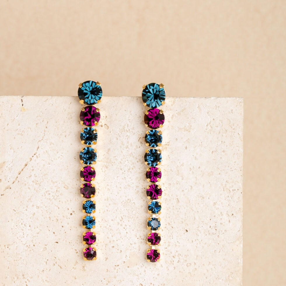 De Joanne-oorringen zijn een ode aan levendige elegantie, met prachtige glazen steentjes in diverse schitterende kleuren. Kies uit blauw, amethist of champagne &ndash; of maak een gedurfde statement (lange oorbellen) met de krachtige bordeauxrode, groene of blauwe tinten. De Joanne-oorringen zijn ontworpen om het licht te vangen en alle aandacht naar zich toe te trekken, perfect voor feestjes of elke gelegenheid die om een ​​vleugje glamour vraagt. Deze oorbellen zijn gemaakt om te stralen, net als jij.
