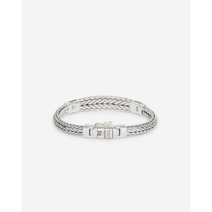 Ontdek de elegantie en kracht van de Ellen XS Steen Armband. Deze prachtige armband heeft een opvallende tijgeroog steen met een kenmerkende marineblauwe kleur, waardoor het een uniek en opvallend accessoire is. De blauwe tijgeroogsteen is een symbool van kracht. Het roept moed op, verdiept de wilskracht en helpt degenen die het dragen om allerlei uitdagingen in hun leven te overwinnen. De zilveren armband heeft een dikker middenstuk dat de Ellen-schakel benadrukt. Elk stuk wordt met de hand gevlochten op basis van een traditionele Aziatische vlechttechniek. Je koopt onze sieraden niet, maar je geeft ze cadeau. Aan