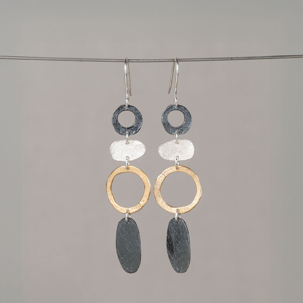 Deze oorhangers combineren drie verfijnde materialen in e&eacute;n ontwerp: 925 sterling zilver, geoxideerd zilver en verguld. De organische vormen en open cirkels zorgen voor een luchtige, speelse uitstraling met een mooi contrast tussen licht en donker. Draag deze oorbellen samen met een mooi collier, een ring en armband voor een complete look!
