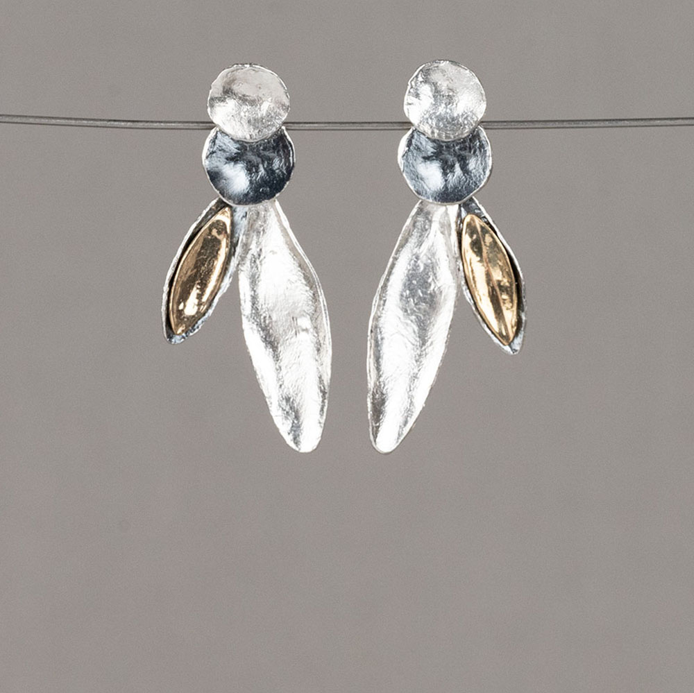 Deze oorbellen vallen op door hun speelse compositie van organische vormen. De gelaagde elementen combineren 925 sterling zilver, geoxideerd zilver en verguld zilver. De licht gehamerde textuur geeft elk element een ambachtelijke uitstraling en laat het licht subtiel weerkaatsen. Door de combinatie van ronde en langwerpige vormen ontstaat een dynamisch en elegant silhouet. Een tijdloos ontwerp dat moeiteloos een moderne en stijlvolle touch aan elke outfit toevoegt.
